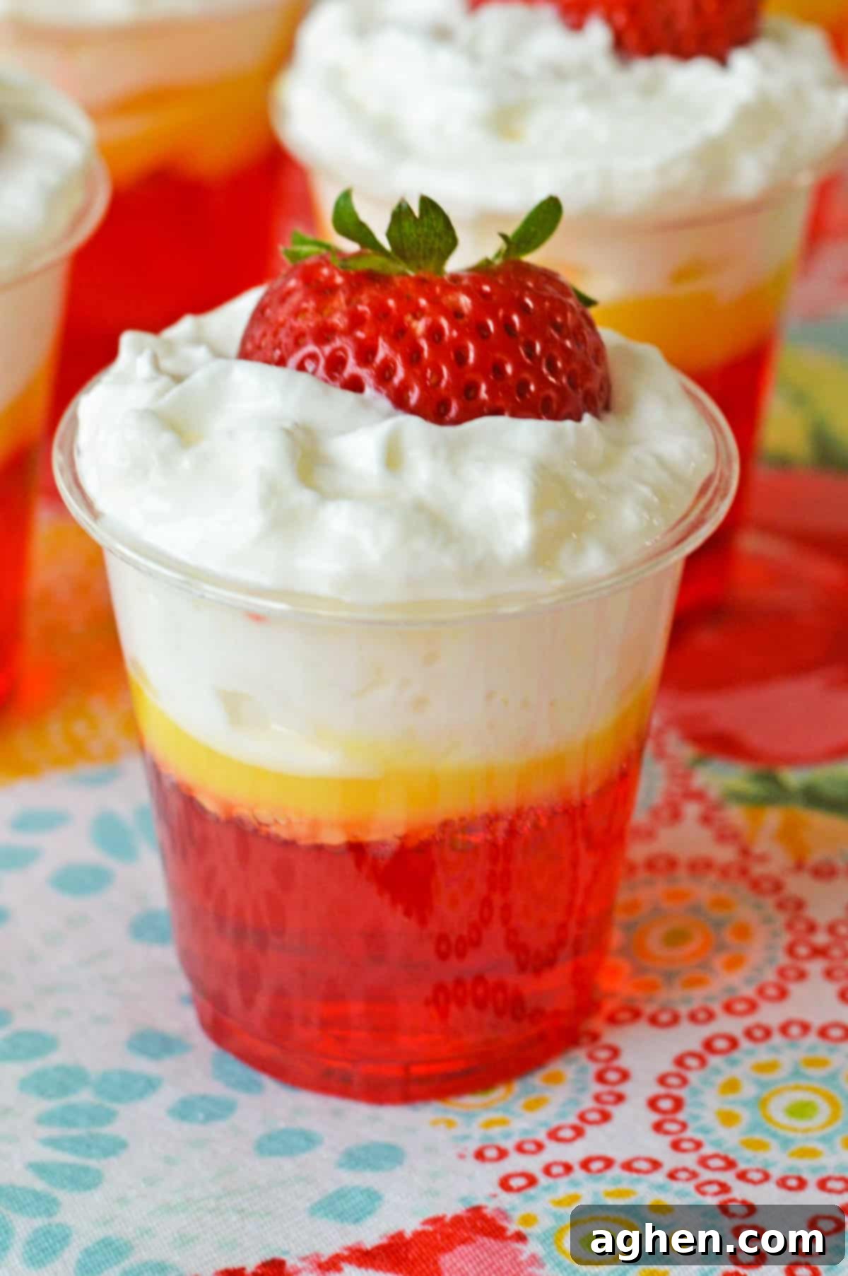 Strawberry and cream vodka jello shots topped with whipped cream and strawberry slice.