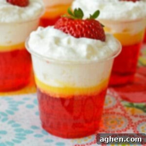 Strawberries and cream jello shots with 3 distinct layers: Strawberry jello, vanilla pudding, and whipped cream.