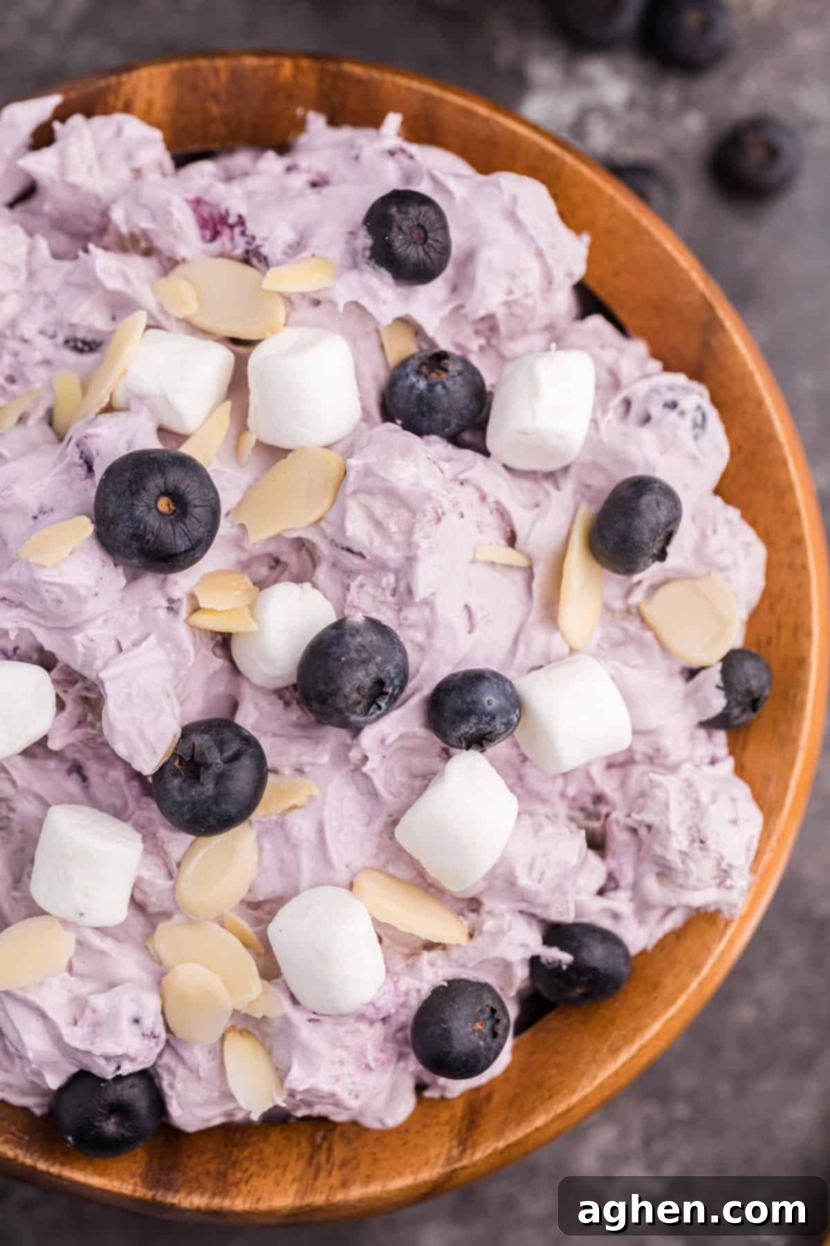 Light and creamy blueberry fluff dessert salad topped with blueberries, marshmallows, and sliced almonds, presented in an elegant bowl.