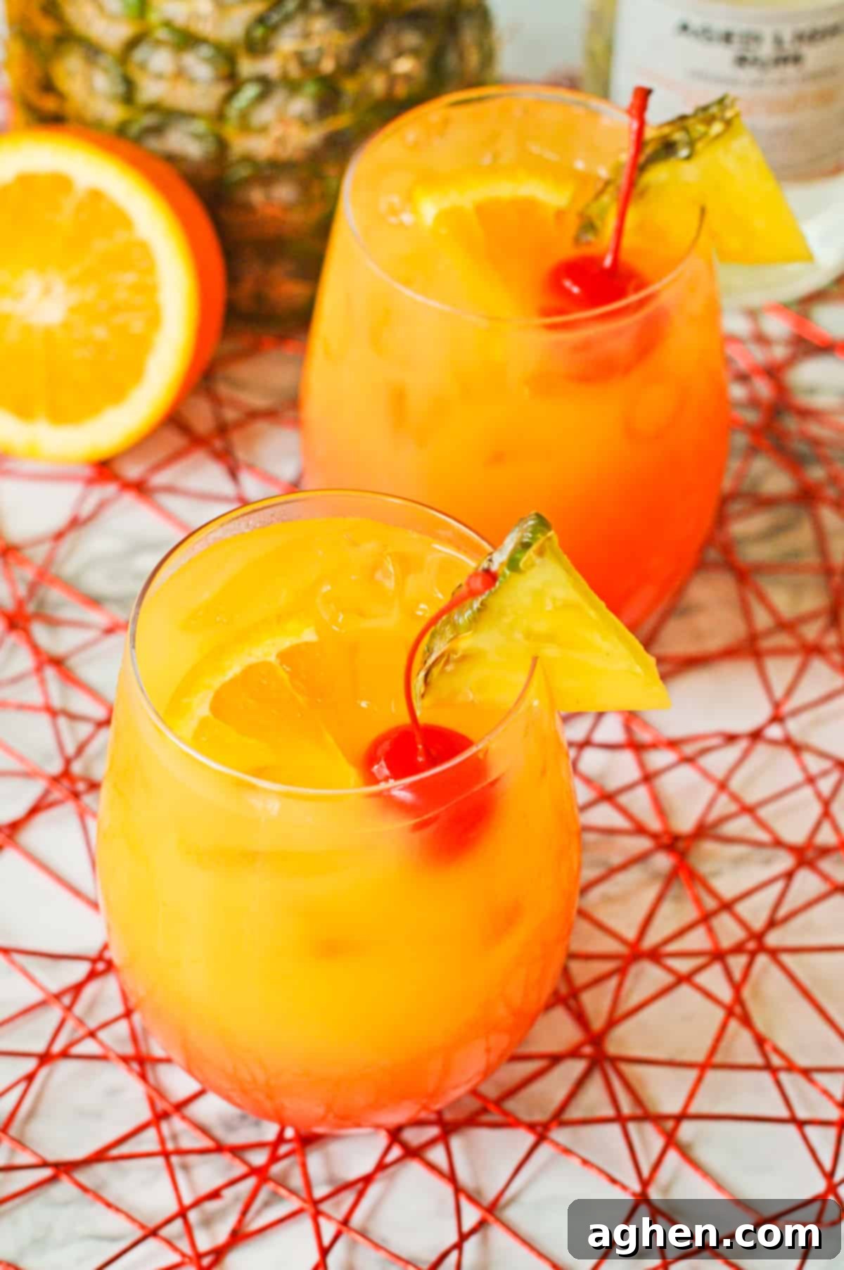 Rum Punch Cocktails with pineapple wedges, cherries, and orange slices.