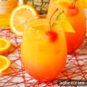 Yellow, orange, and red cocktail with cherry, pineapple, and oranges.