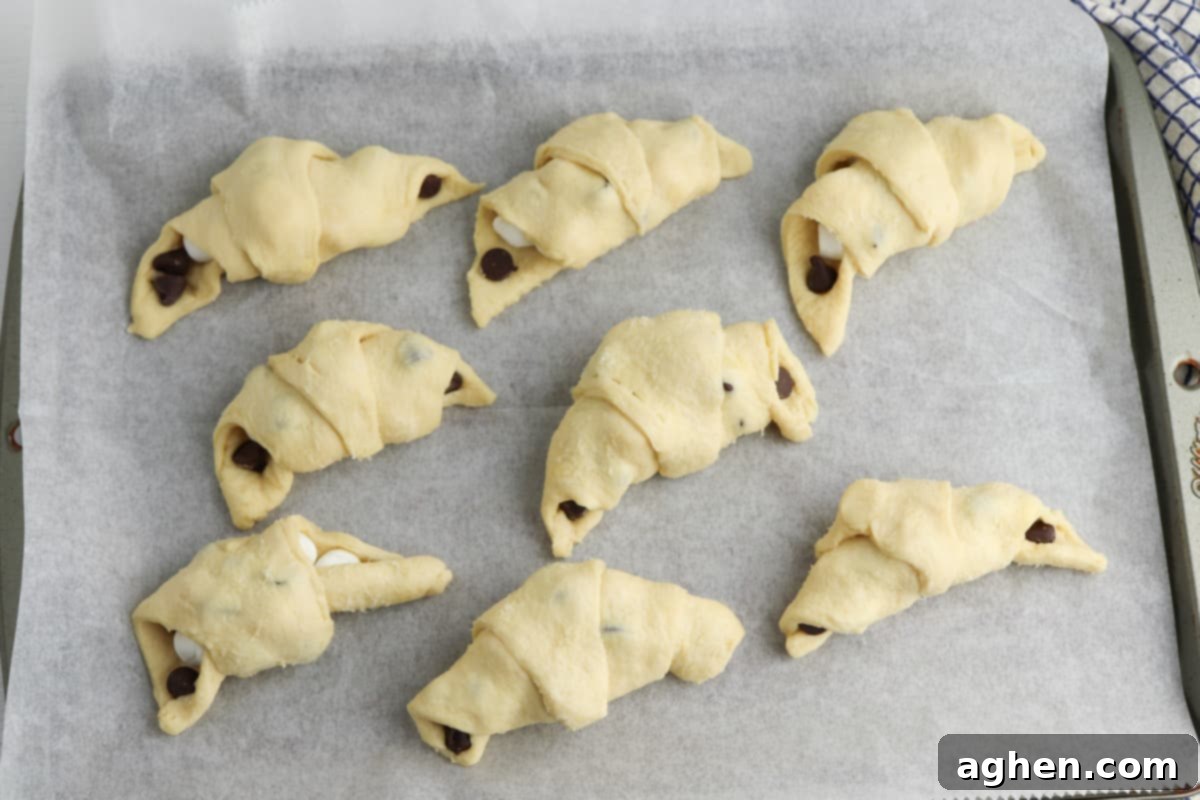 Crescent dough smores roll ups on parchment lined baking sheet.