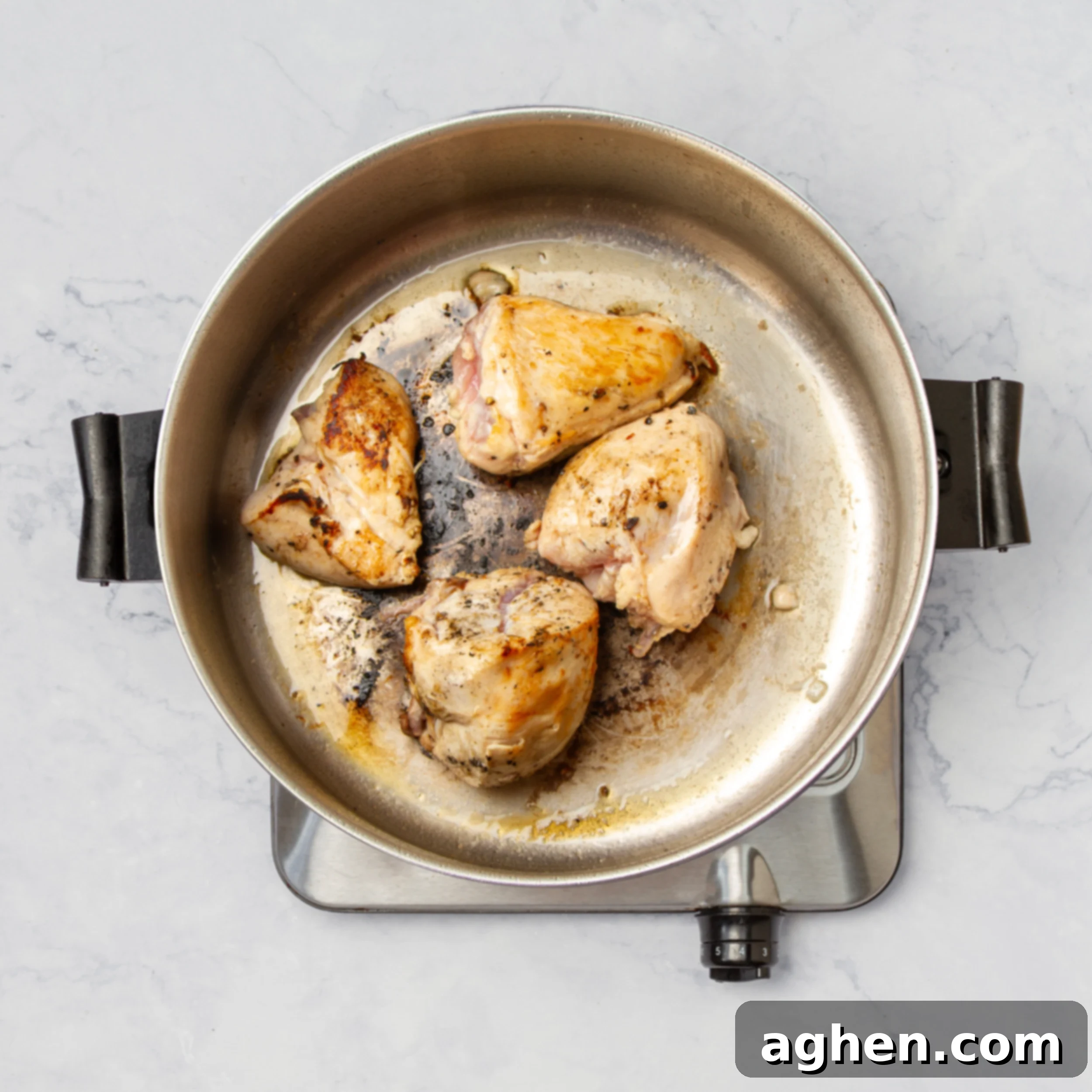 Seasoned chicken cooking in a pan. 
