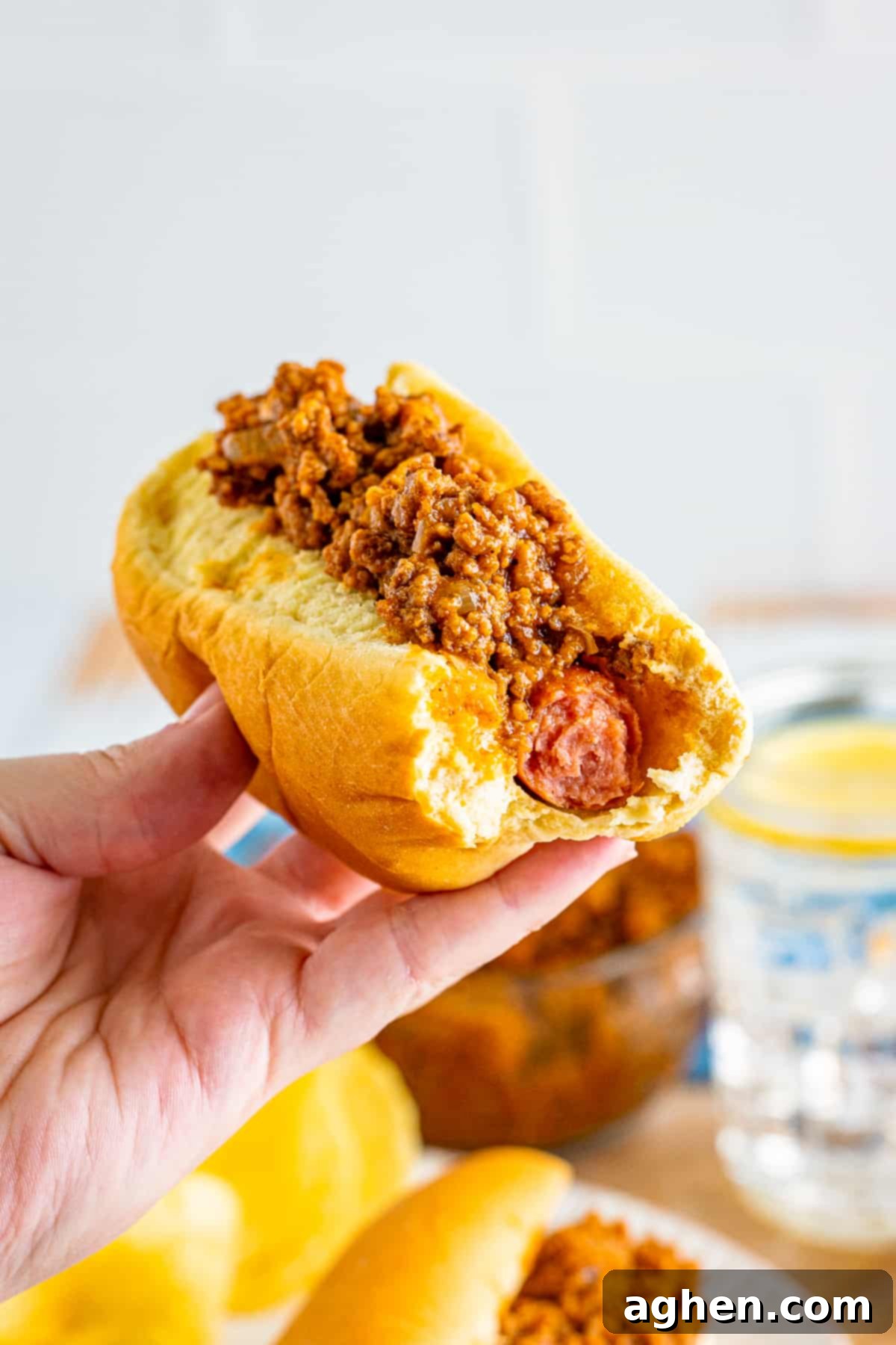 Chili topped hot dog with a bite taken out of it.
