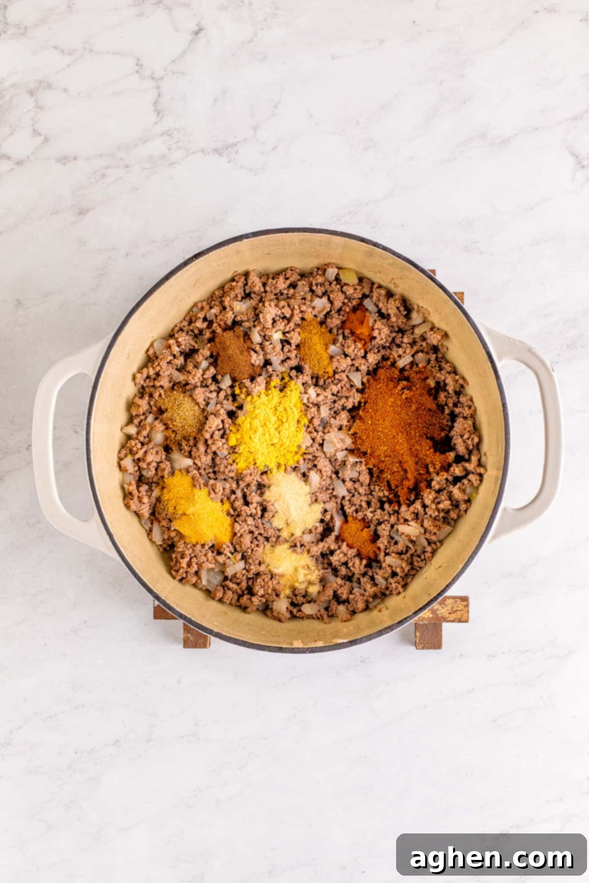 Spices and seasonings on top of ground beef in dutch oven.