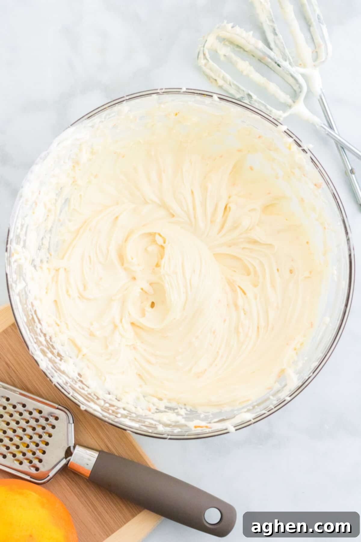 Large glass bowl with whipped cream cheese fruit dip. Hand mixer beater attachments are next to the bowl.