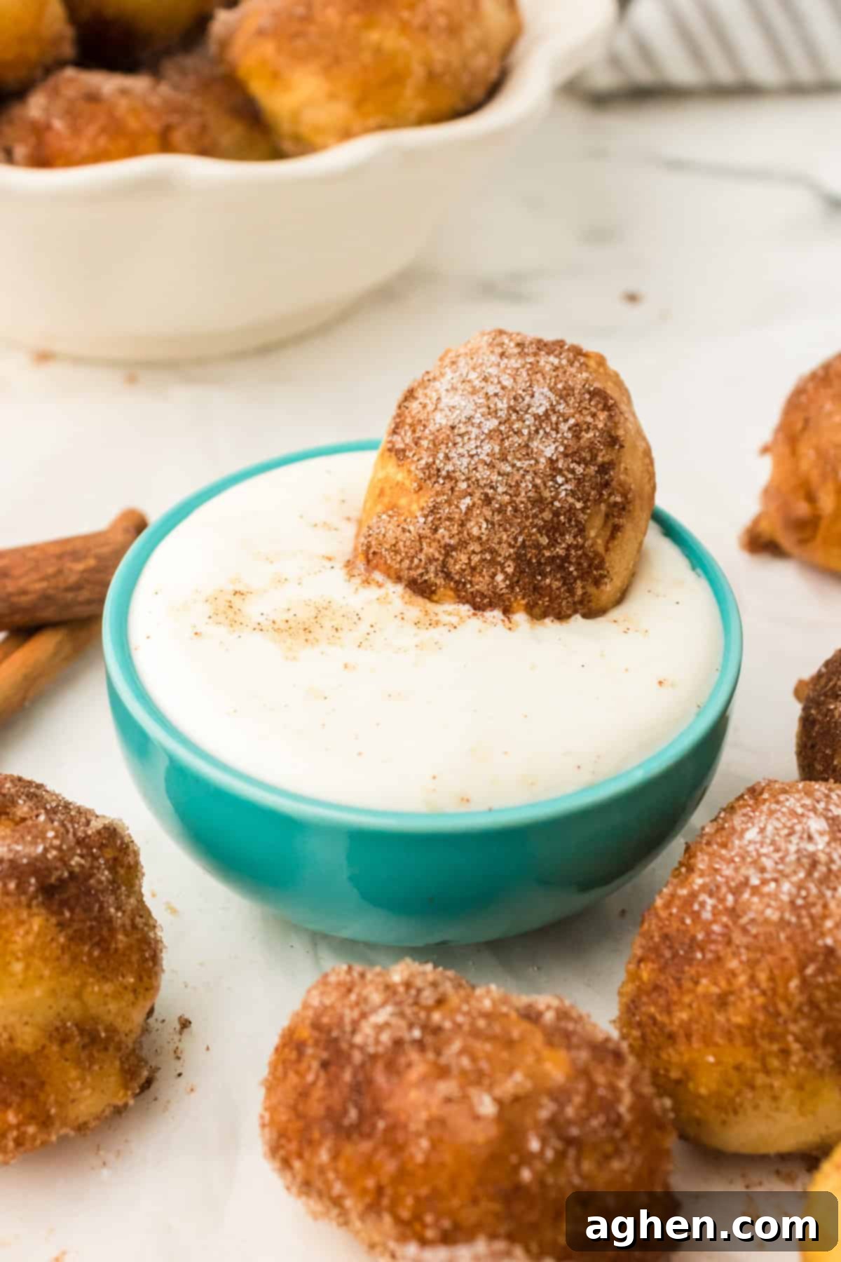 Cinnamon pretzel bite dipped in white creamy sauce.