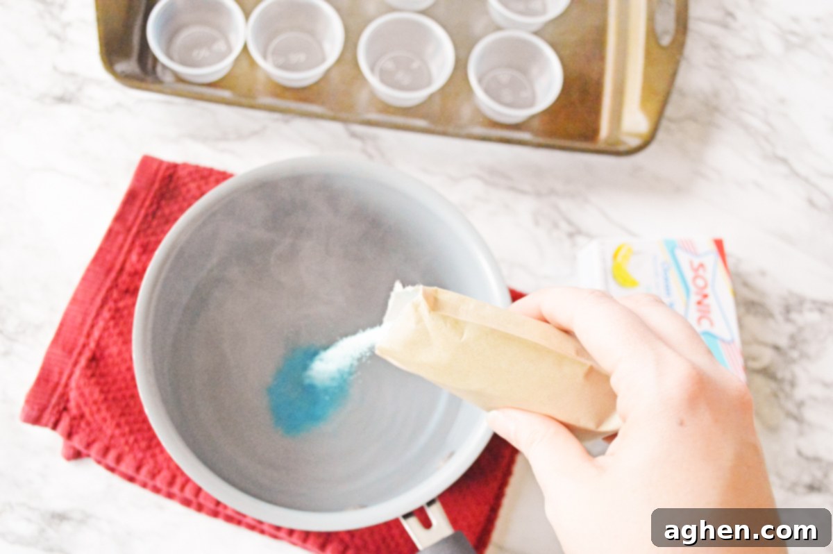 Blue ocean water jello mix being vigorously whisked with boiling water in a small saucepan to fully dissolve.