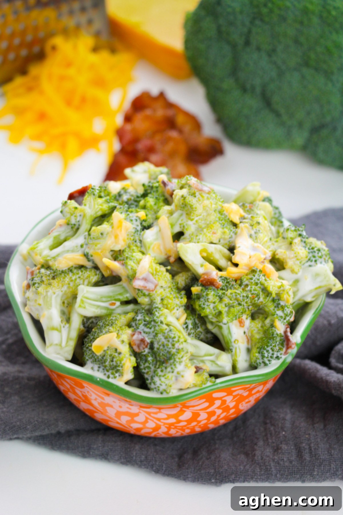 Creamy Bacon Cheddar Broccoli Salad 2 Broccoli salad with bacon and cheddar cheese in orange and green serving bowl.