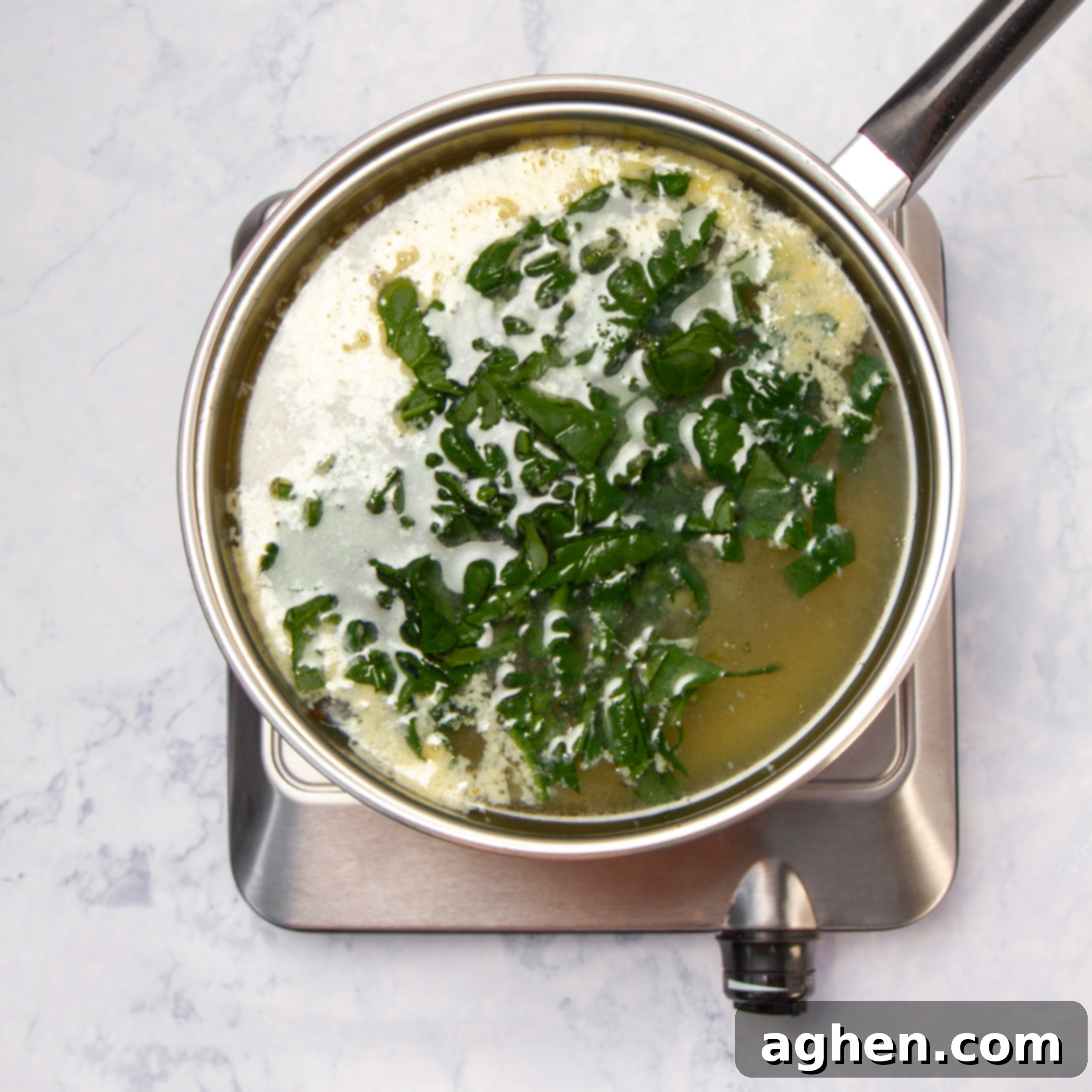 Classic Italian Stracciatella Soup 6 Stracciatella Soup broth simmering on the stove top with fresh herbs and egg mixture added.