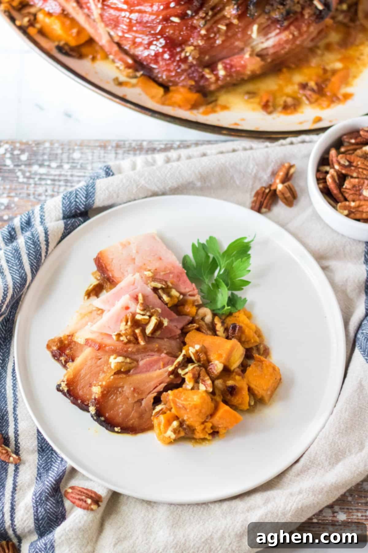 Decadent Pecan Praline Glazed Ham 3 Close-up of a beautifully sliced maple pecan ham, revealing its juicy interior and crispy topping, served with sweet potatoes.
