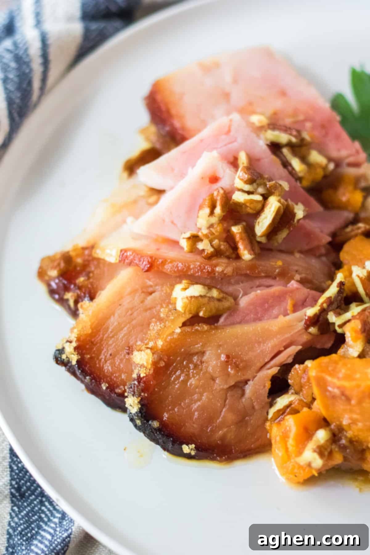 Decadent Pecan Praline Glazed Ham 10 Plates with individual slices of pecan glazed spiral ham topped with more pecans, alongside a serving of roasted sweet potatoes, ready to be enjoyed.