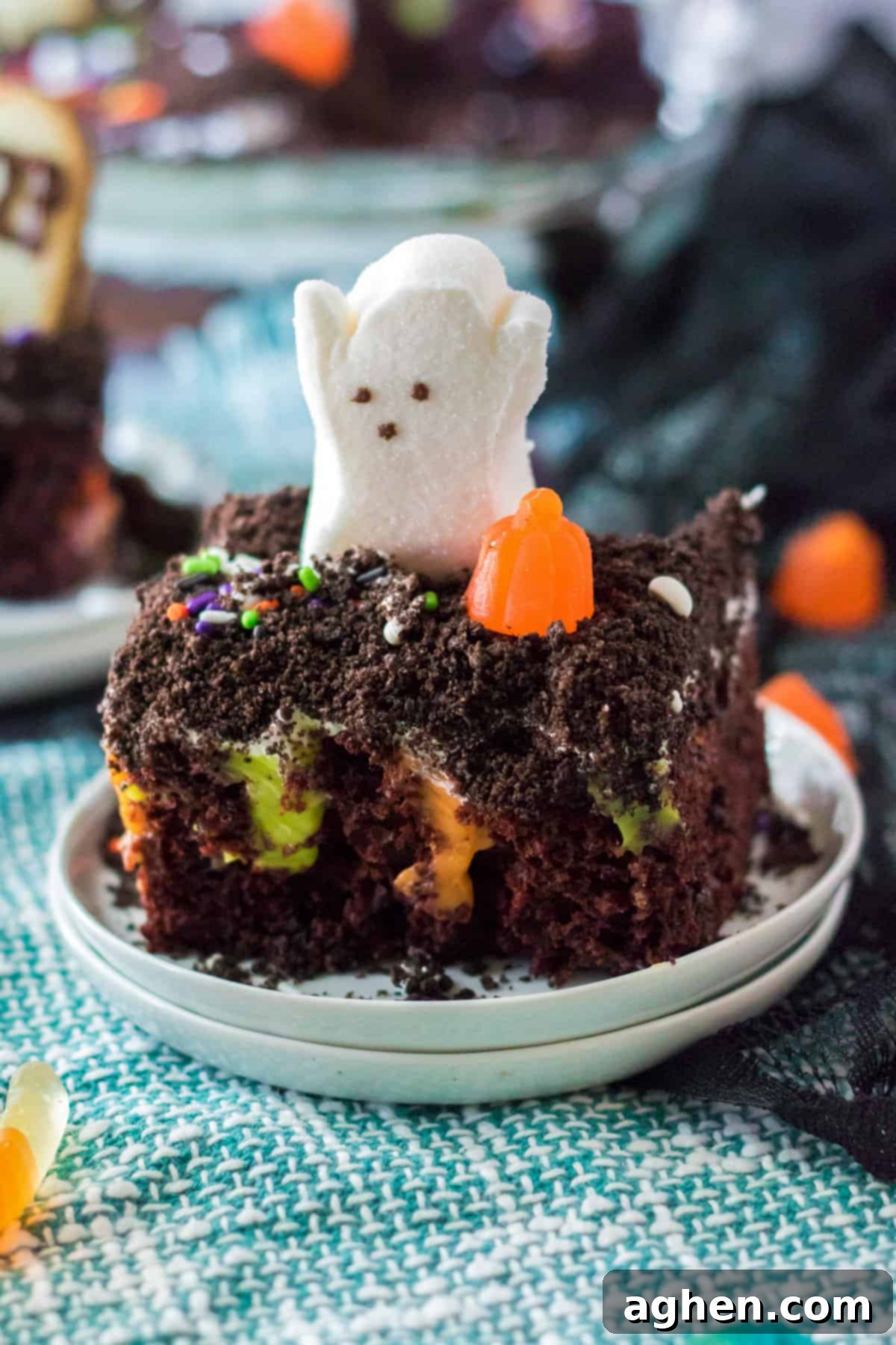 Piece of halloween poke cake with ghost and pumpkin candy on top.