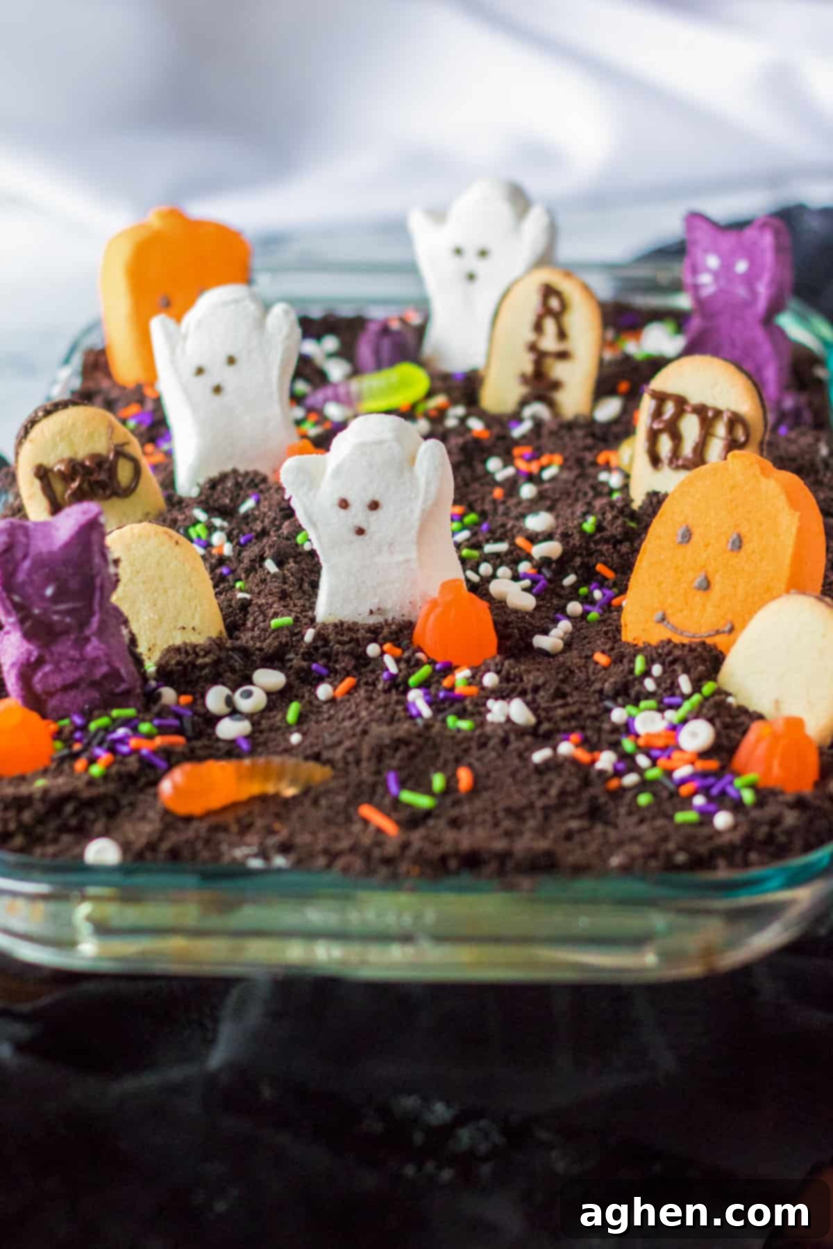 Ghosts in the Graveyard Dessert topped with peeps ghosts, cookie tombstonea, and other Halloween candy.