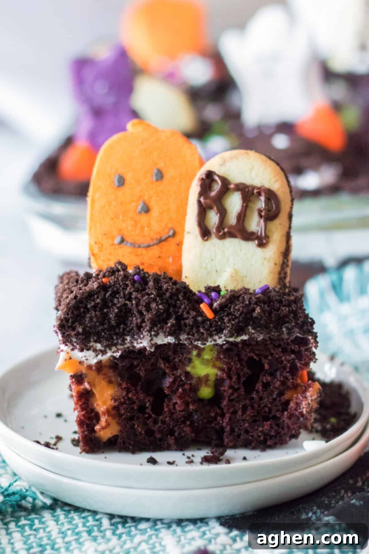 Piece of Ghosts in the Graveyard poke cake with cookie tombstone and candy pumpkin.