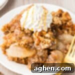 Apple crisp topped with dollop of whipped cream and caramel drizzle.