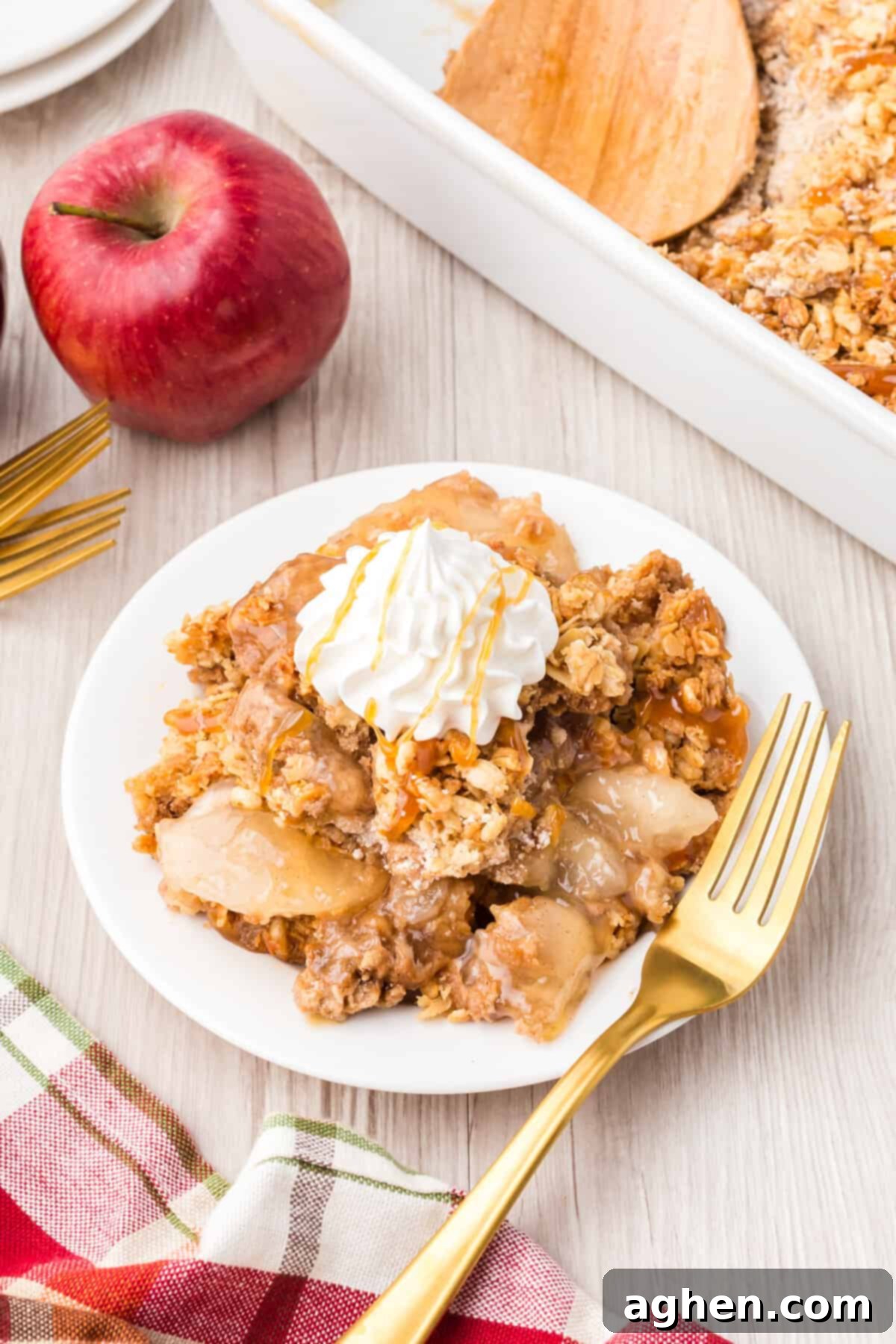 Serving of apple crisp topped with caramel sauce and whipped cream.