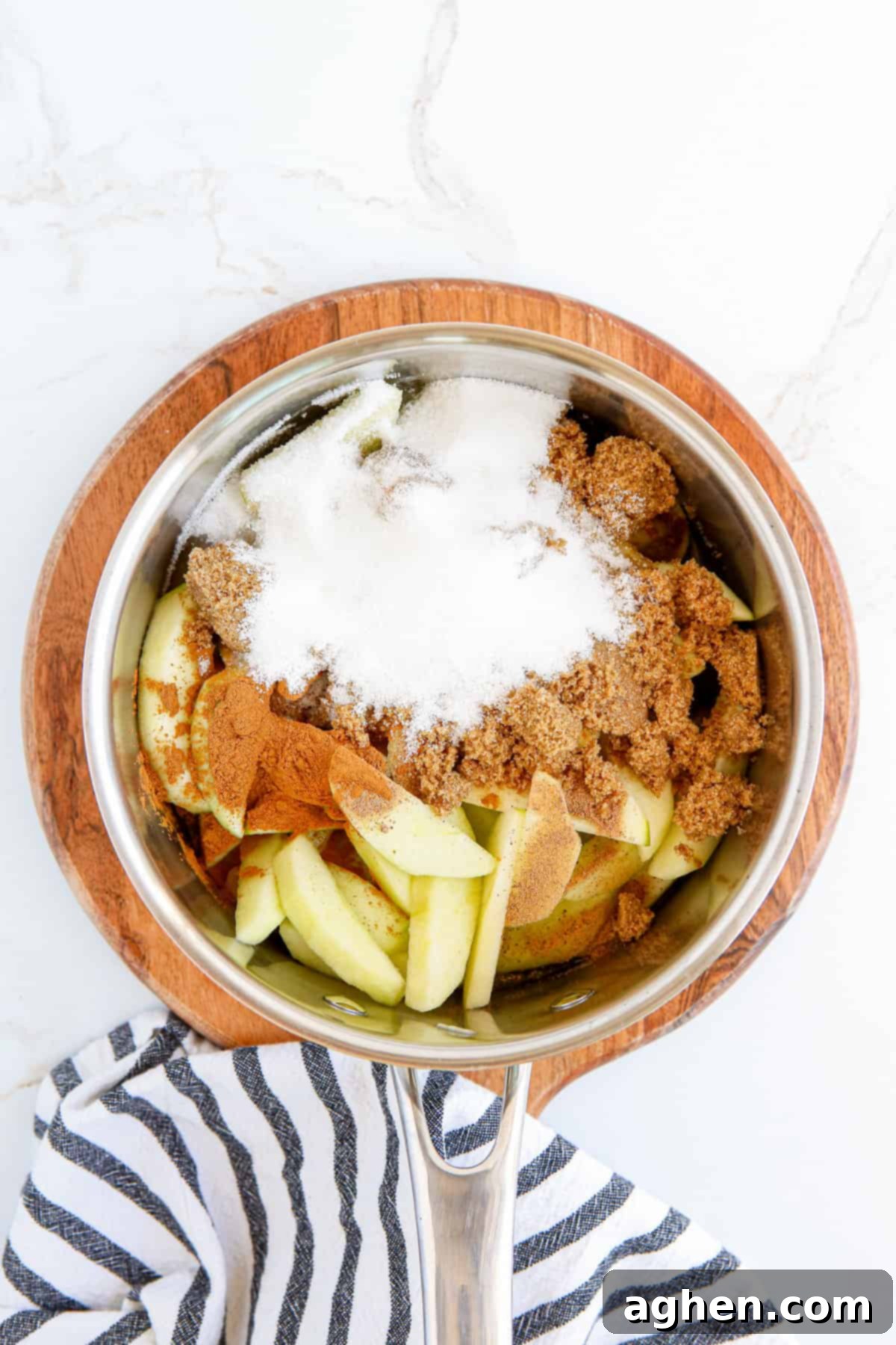 All ingredients for homemade apple pie filling, including apples, sugars, and spices, combined in a pot on the stovetop, ready for cooking.