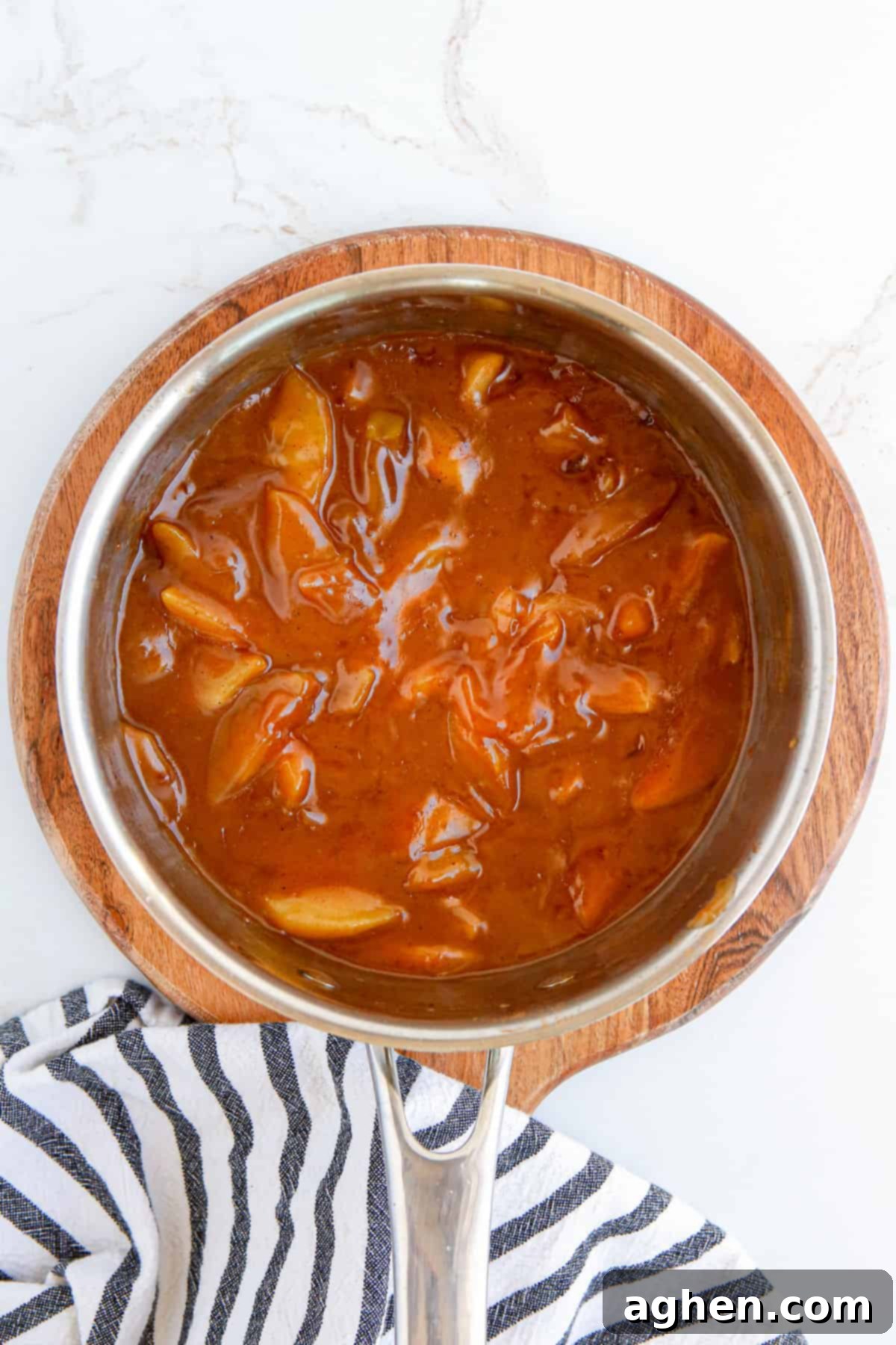 A pot of finished homemade apple pie filling, rich and thick, resting on the stovetop to cool.