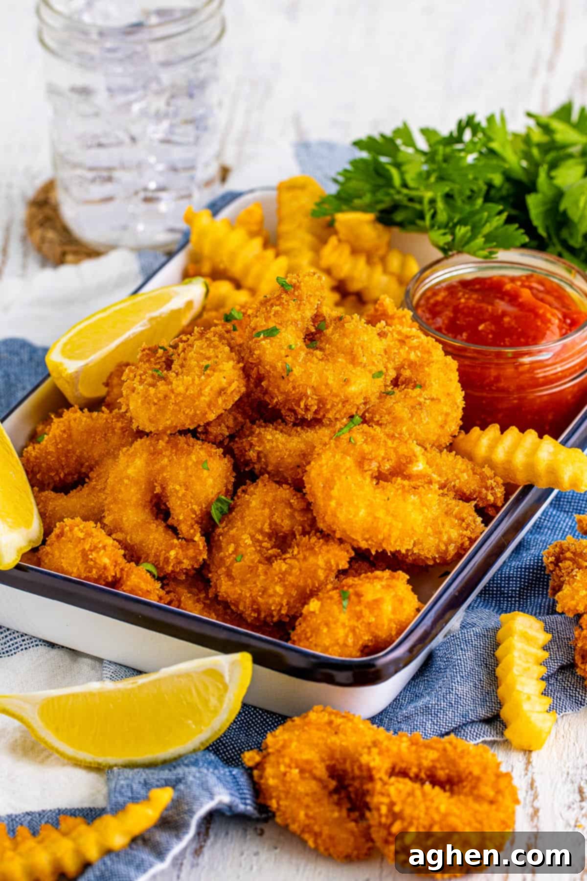 Panko breaded fried shrimp served with cocktail sauce, lemon wedges, and french fries.