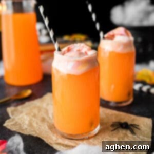 Hocus pocus punch - an orange drink topped with rainbow sherbet and a black and white paper straw.