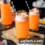 Hocus pocus punch - an orange drink topped with rainbow sherbet and a black and white paper straw.