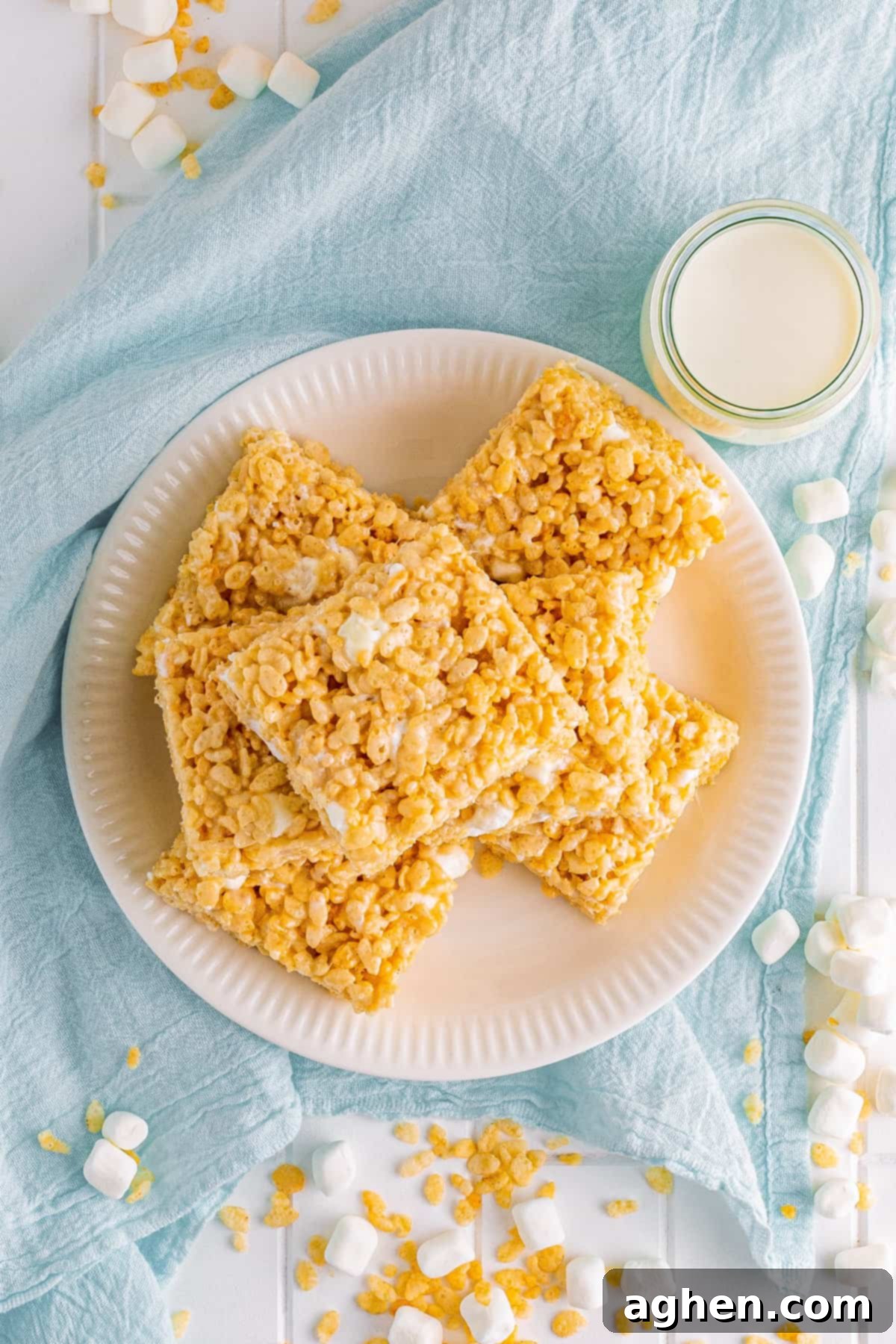 A top-down photo of a white plate filled with perfectly cut bakery-style Rice Krispies Treats, ready to be enjoyed.