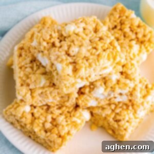 Bakery-style Rice Krispies Treats, perfectly sliced into squares and enticingly piled on a pristine white plate, promising gooey deliciousness.