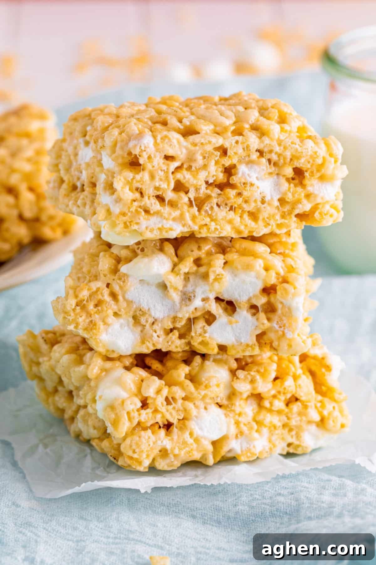 Three perfectly thick and gooey bakery-style Rice Krispies Treats, stacked enticingly, revealing their soft, chewy interior.