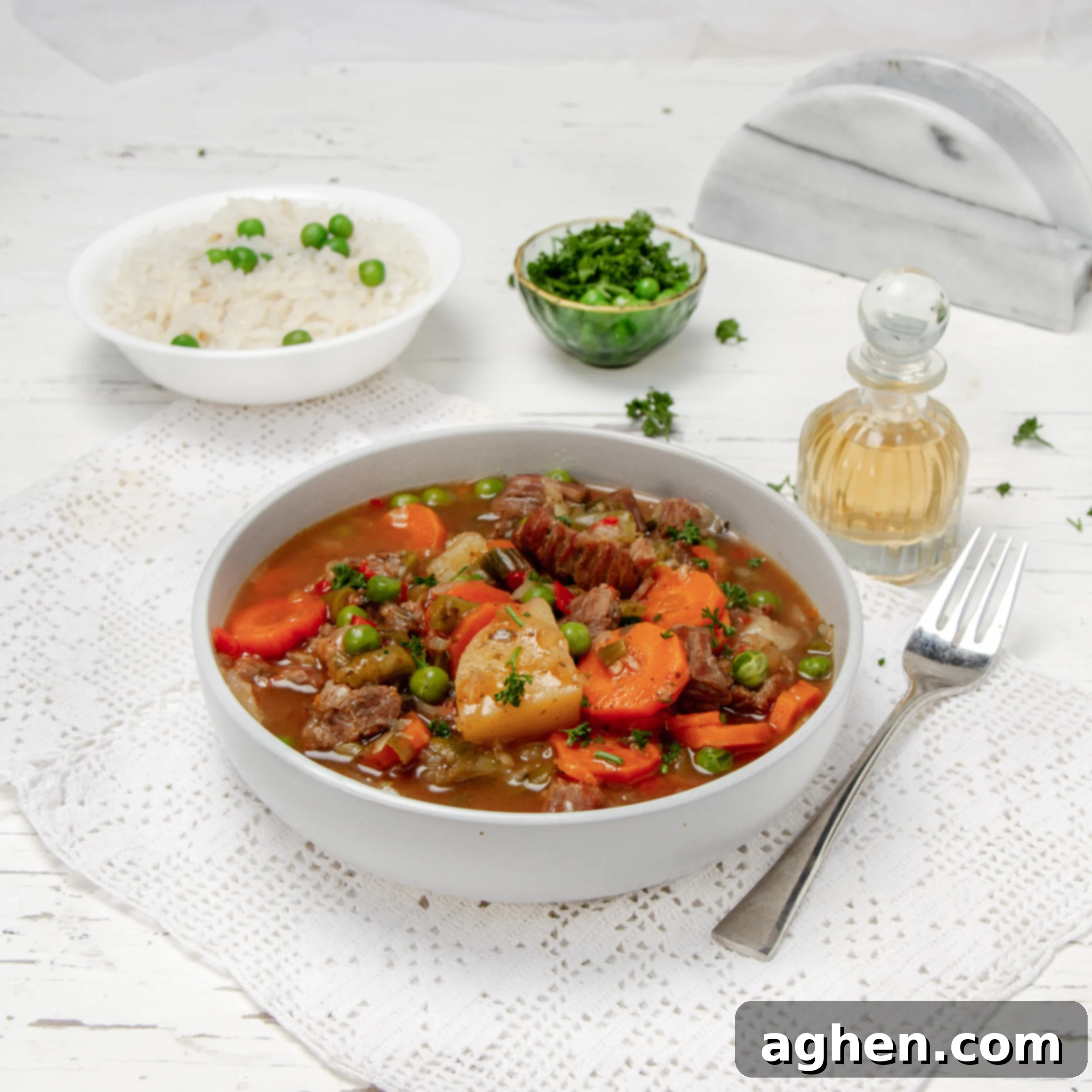 The Improvised Feast 2 Hearty and comforting Milligan Stew in a bowl with a bowl of fresh herbs and rice on the side.