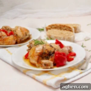 Delicious Italian Chicken Scarpariello with baby red peppers on a plate with bread ont he side.