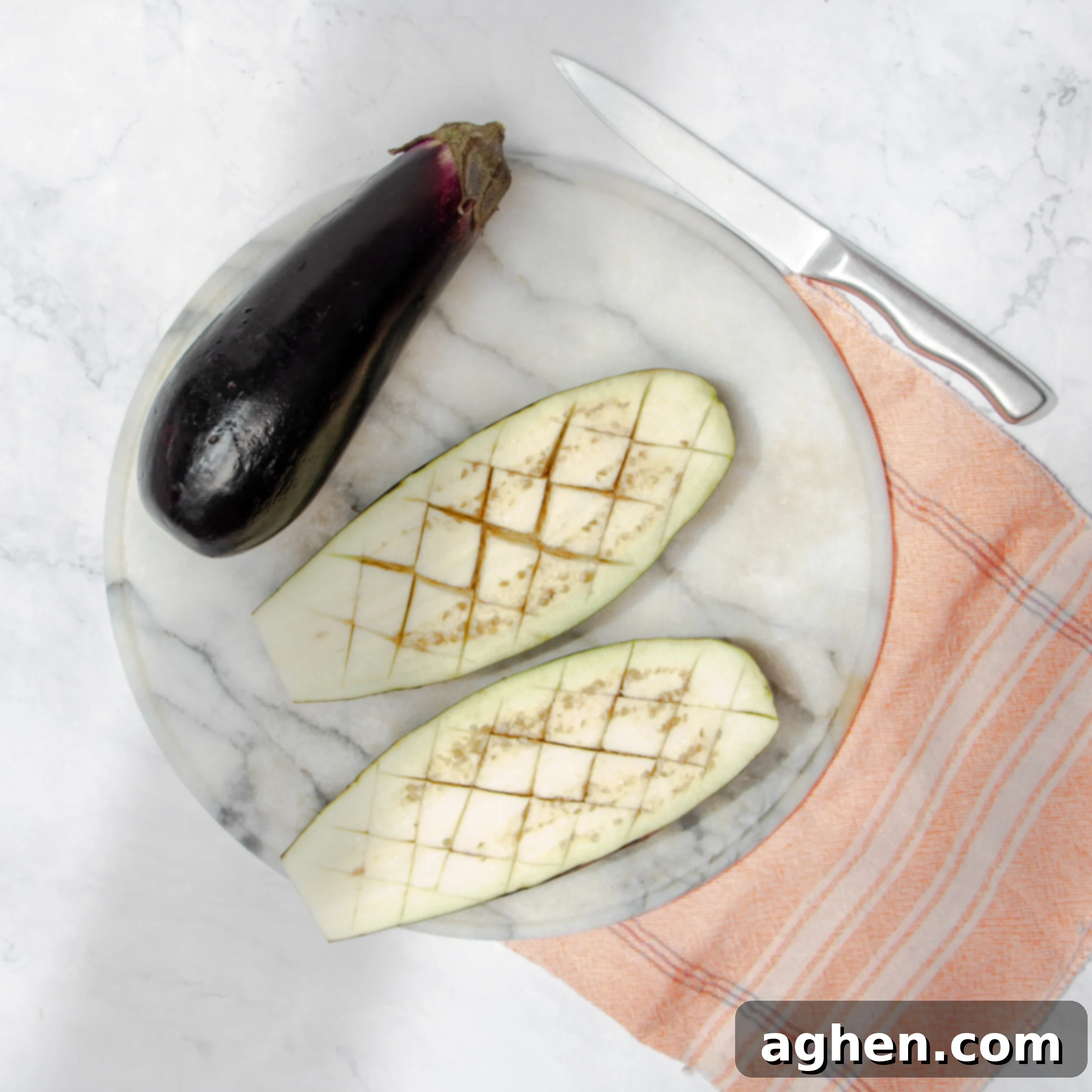 Savory Stuffed Eggplant 4 Scoring the eggplant on a plate with a small kitchen knife.