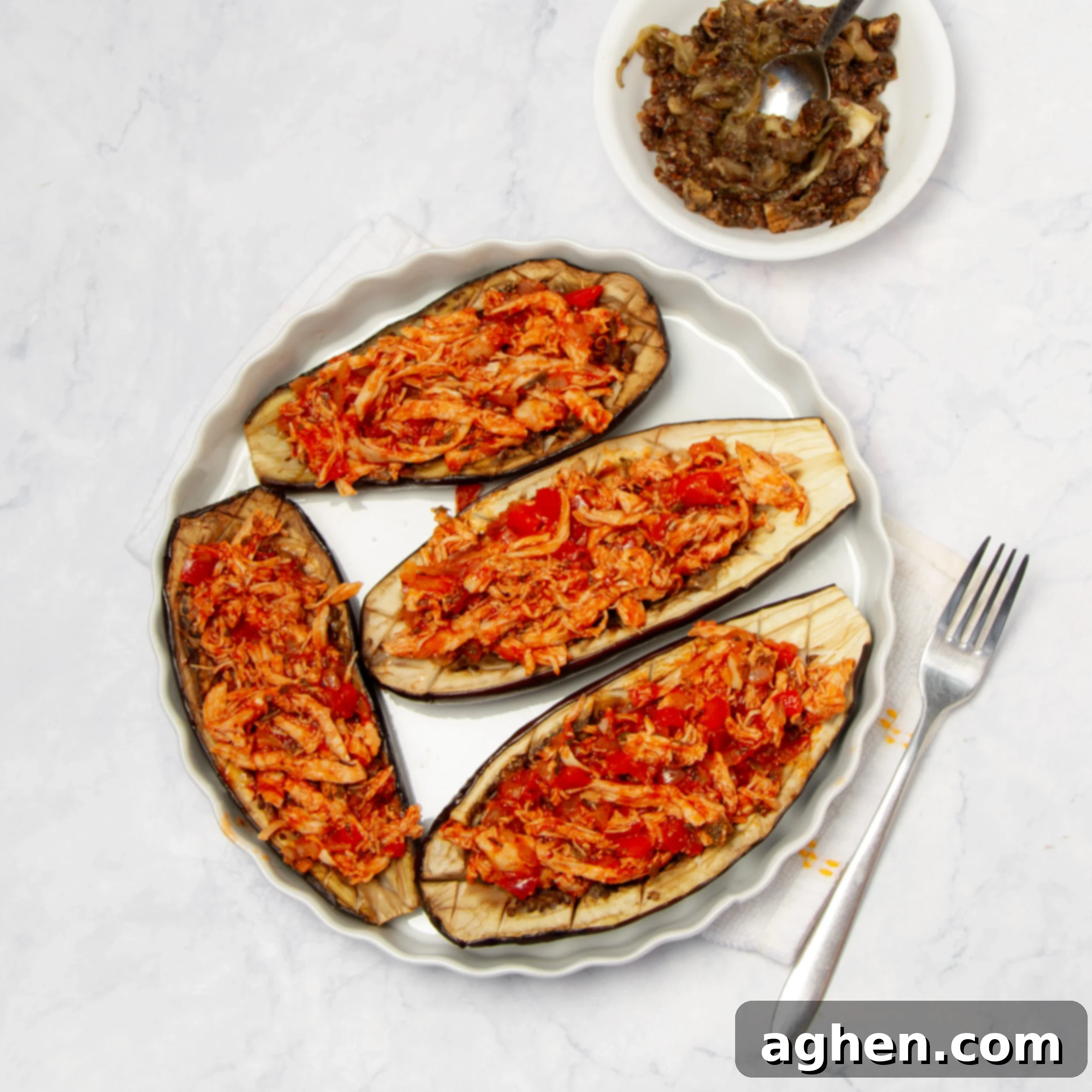 Savory Stuffed Eggplant 7 Hollowed-out eggplants on a plate stuffed with chicken filling.