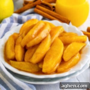 Copycat cracker barrel fried apples served on white plate with cinnamon sticks and juice next to them on the table.