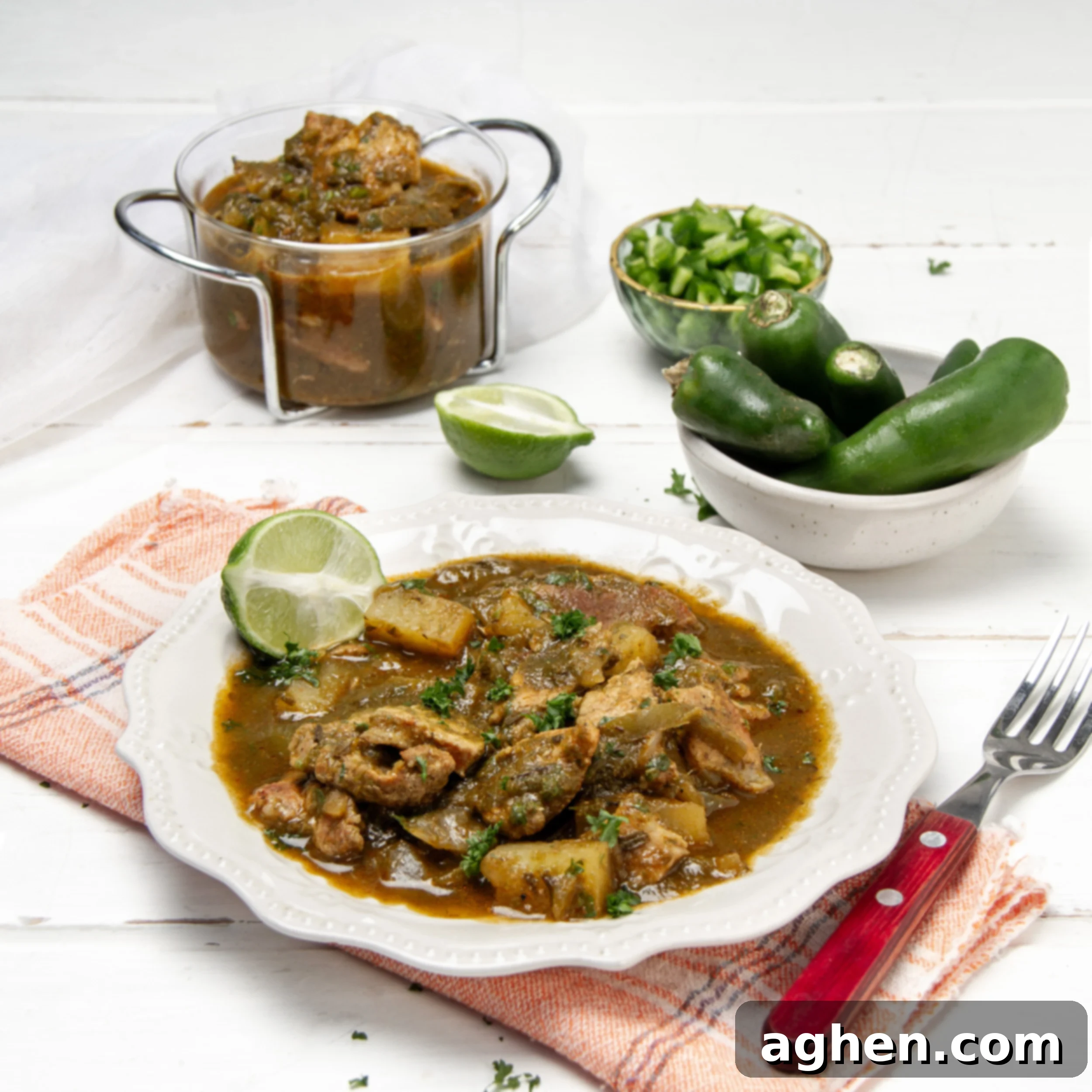 Thick and meaty Green Chili Stew in a bowl with whole peppers on the side.