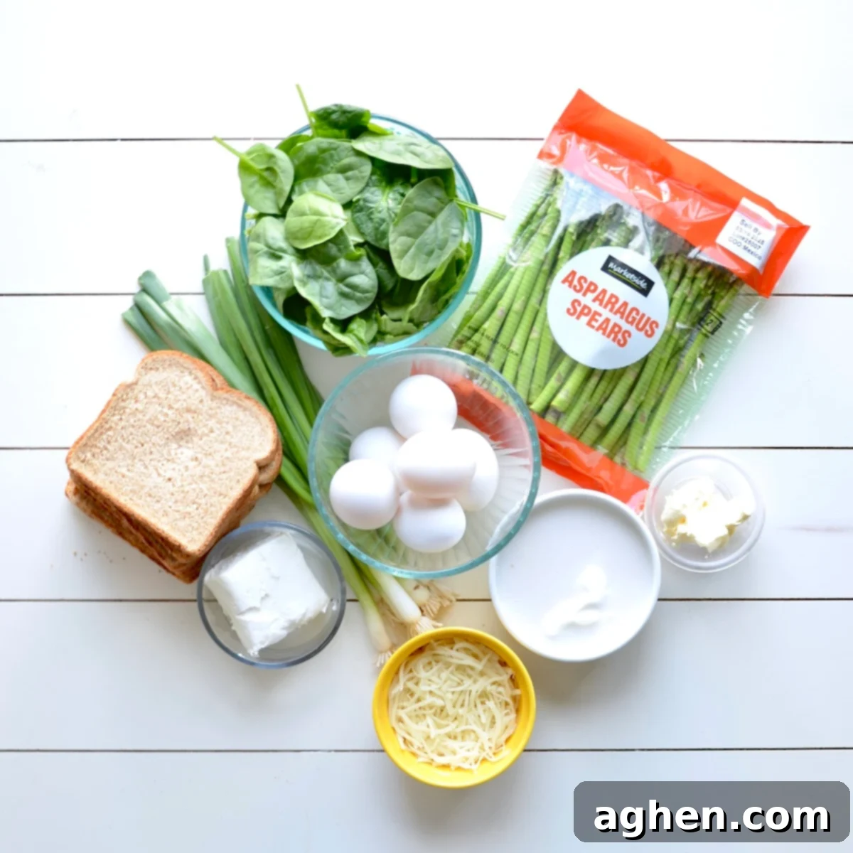 A collection of fresh, colorful ingredients laid out, ready for preparing a healthy vegetable casserole, including asparagus, spinach, eggs, and cheese.