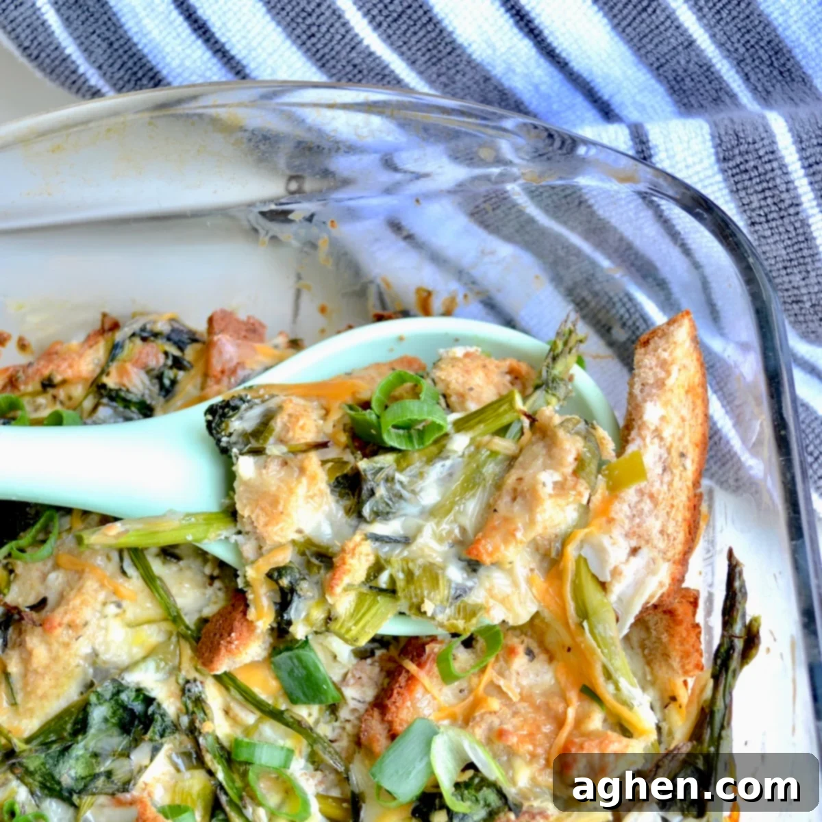 A serving spoon lifting a portion of the baked vegetable casserole from a dish, showing its golden-brown top and tender ingredients.