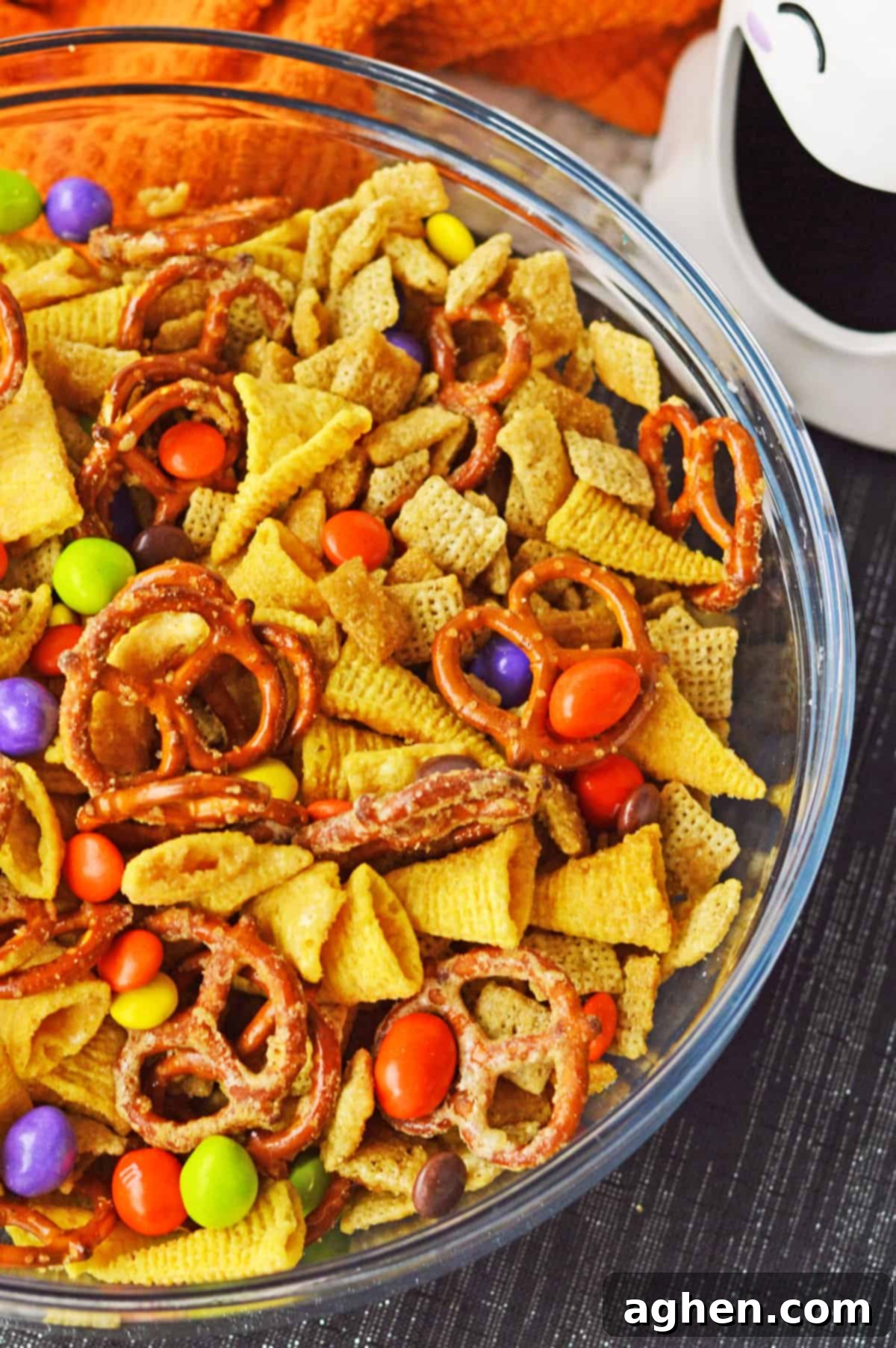 Close-up view of the sweet and salty Halloween Chex Mix, showing individual pieces of Chex cereal, pretzels, Bugles, M&Ms, and Reese's Pieces.