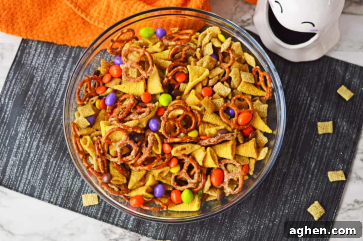 Colorful Halloween snack mix with M&Ms and Reese's Pieces in a large glass bowl, ready for serving.