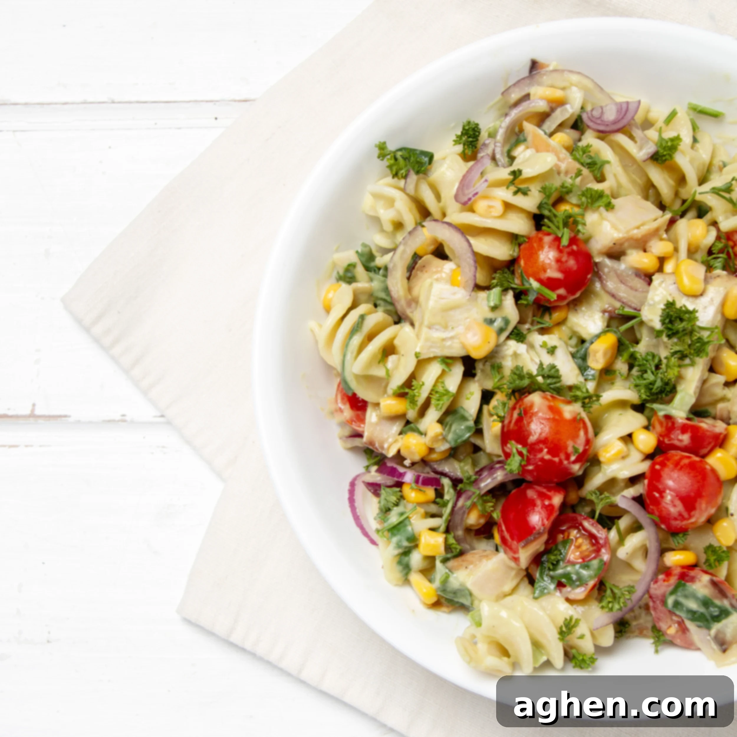 Light and refreshing Spring Chicken Pasta Salad artfully arranged in a rustic wooden bowl, ready to be served. Fresh parsley garnish adds a pop of color, making it an inviting meal.
