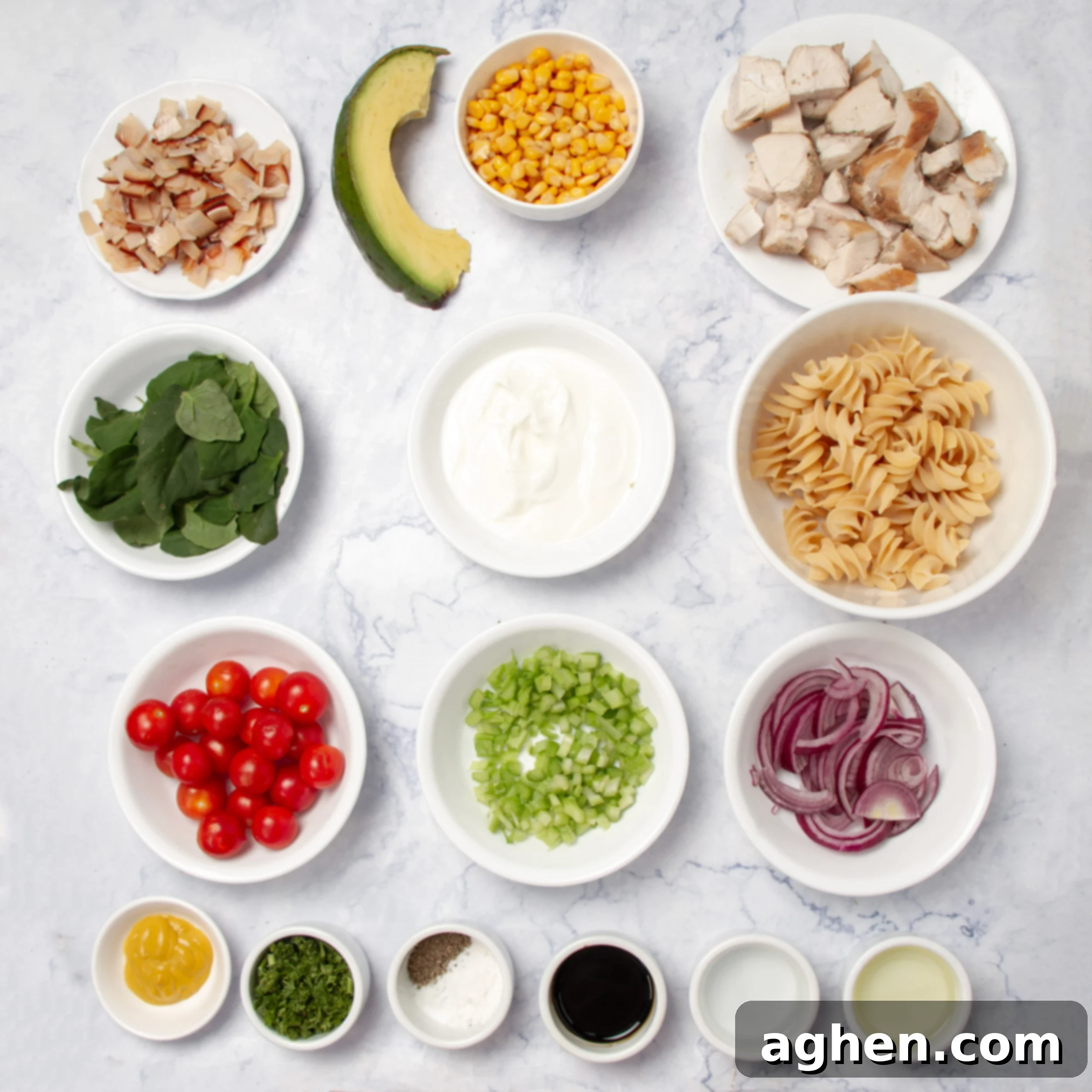 Various fresh ingredients for Spring Chicken Pasta Salad laid out neatly in individual dishes on a kitchen counter, showcasing colorful vegetables, diced chicken, and turkey ham.