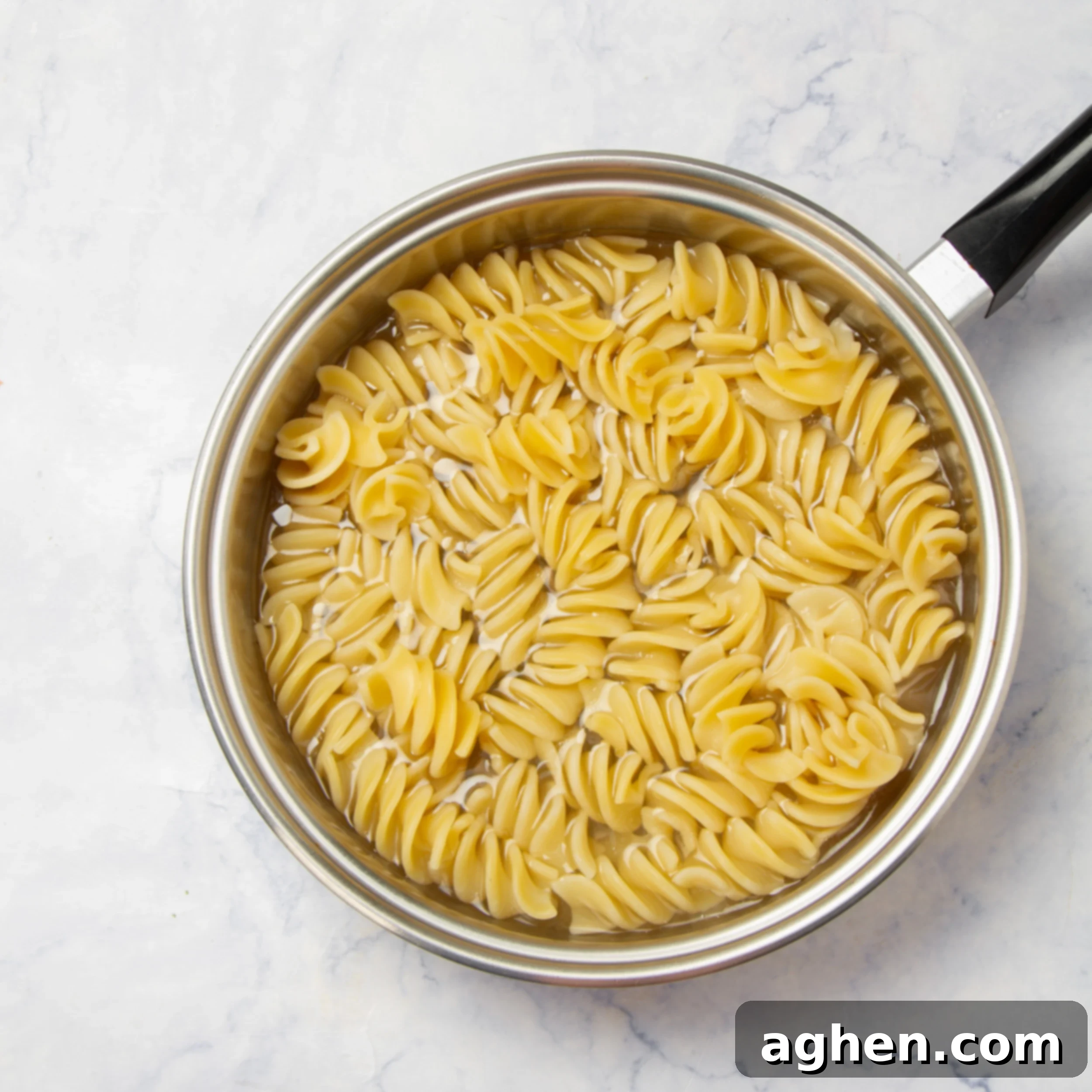 Fusilli pasta cooking in a pot of boiling, salted water on a stovetop, capturing the steam and anticipation of a delicious meal.
