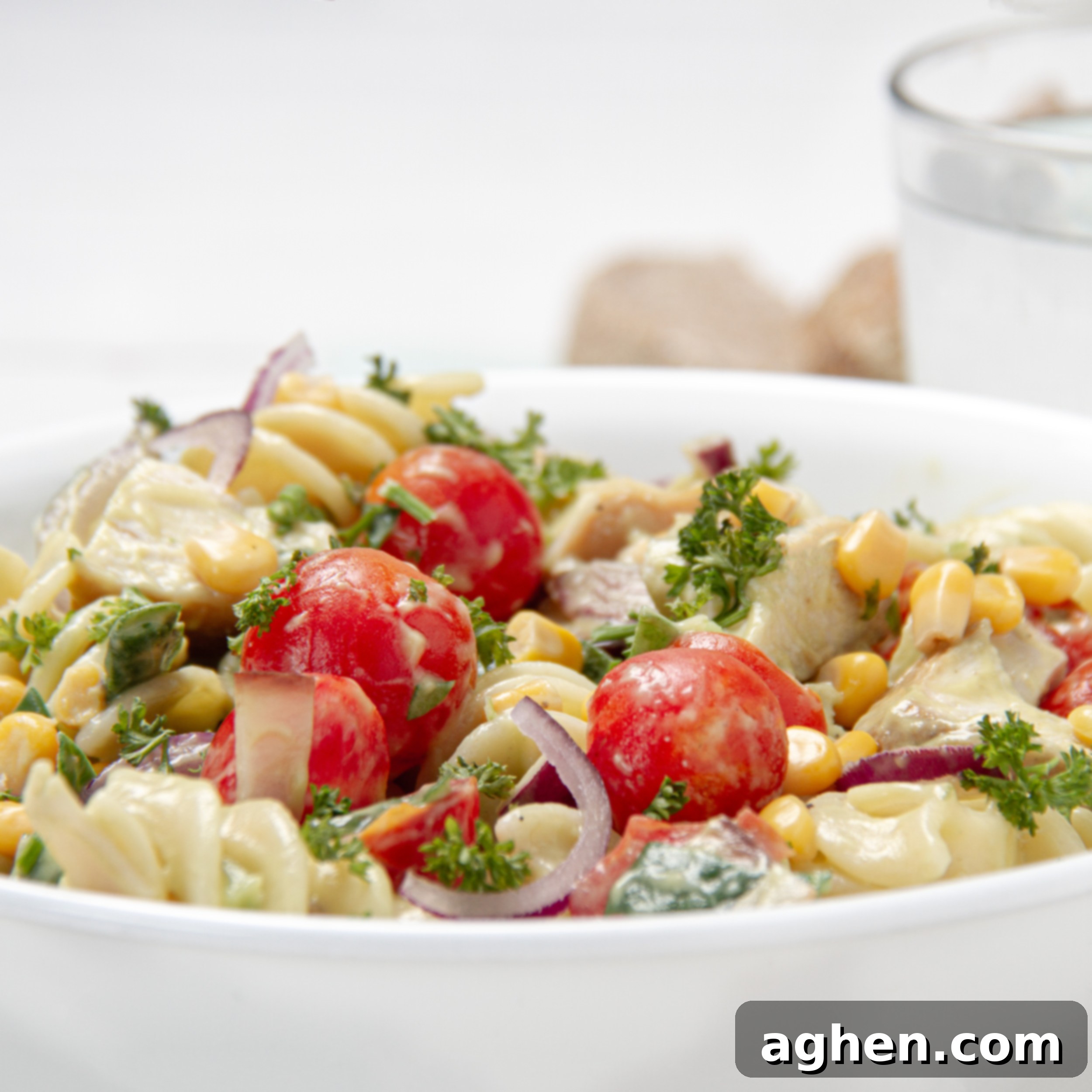 A large mixing bowl filled with Spring Chicken Pasta Salad, perfectly tossed with its creamy dressing, showcasing the colorful blend of ingredients and inviting texture.