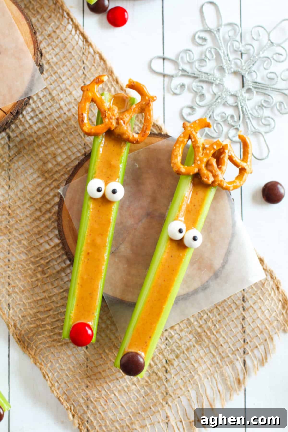 Festive Peanut Butter Antler Crunch 2 Peanut butter filled celery sticks decorated to look like reindeer with candy eyes, pretzels, and M&Ms.