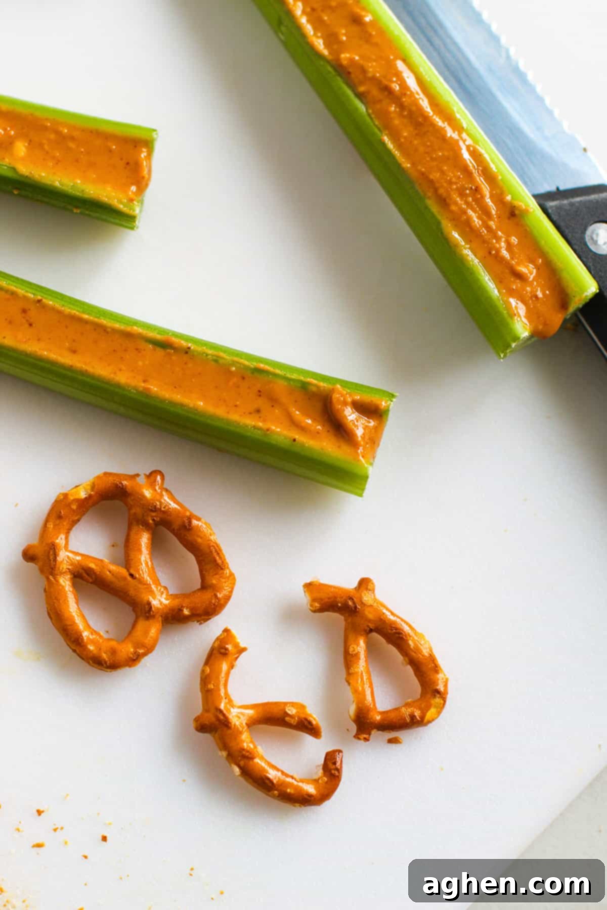 Festive Peanut Butter Antler Crunch 6 Celery sticks filled with peanut butter next to 2 pretzel twists, once broken in half.