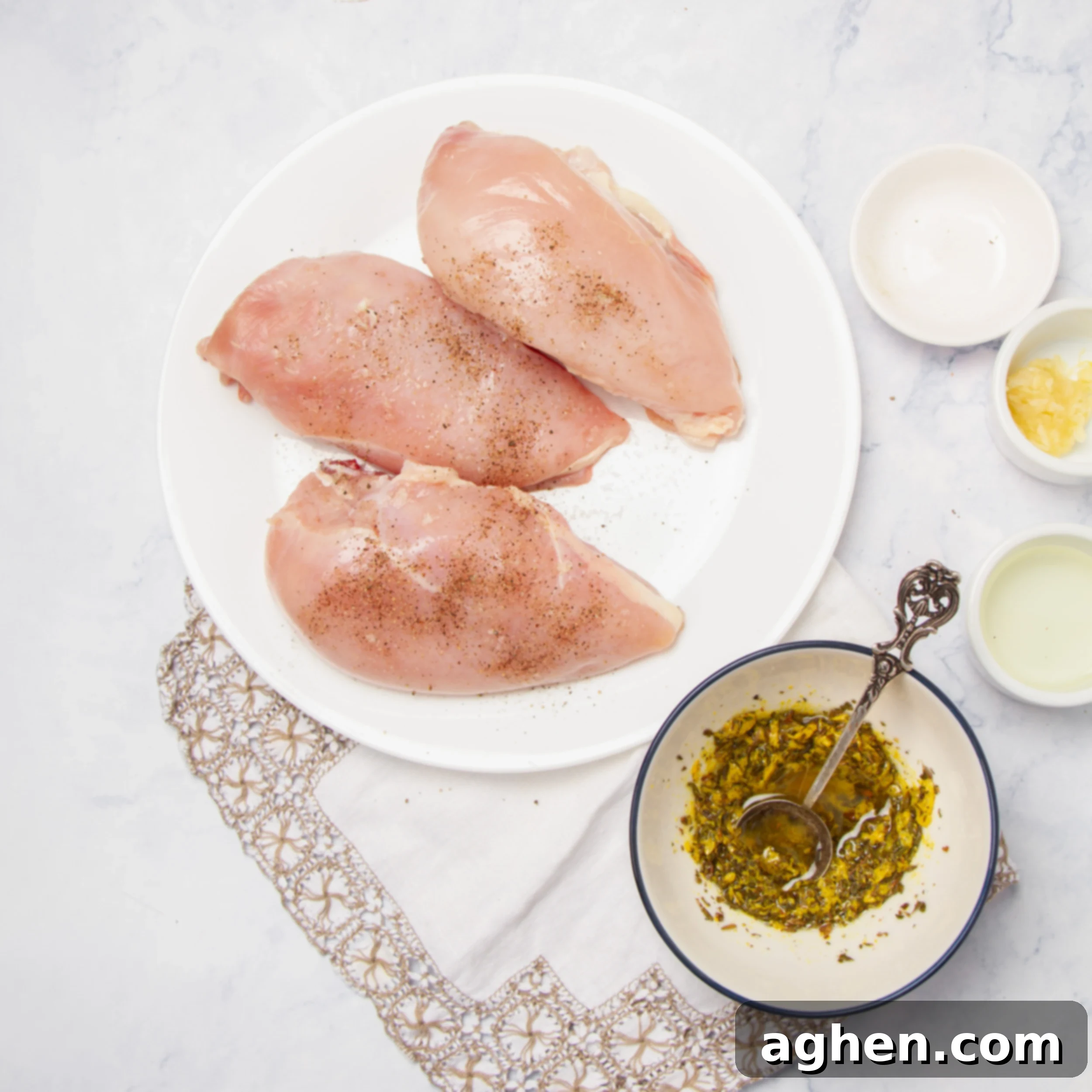 Marinade mixed in a small bowl, next to a plate of three raw chicken breasts. 