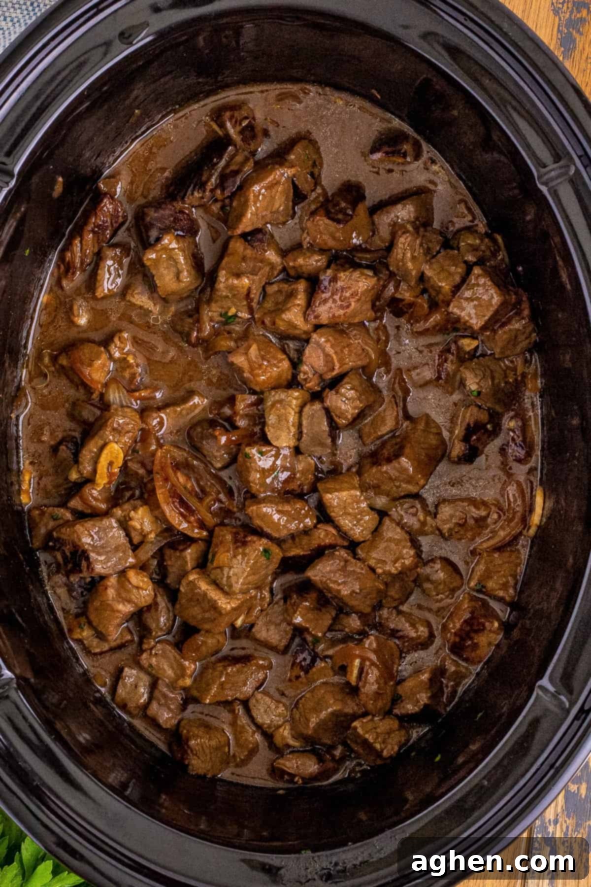 Crockpot steak bites in au jus sauce with garlic and sweet onions.