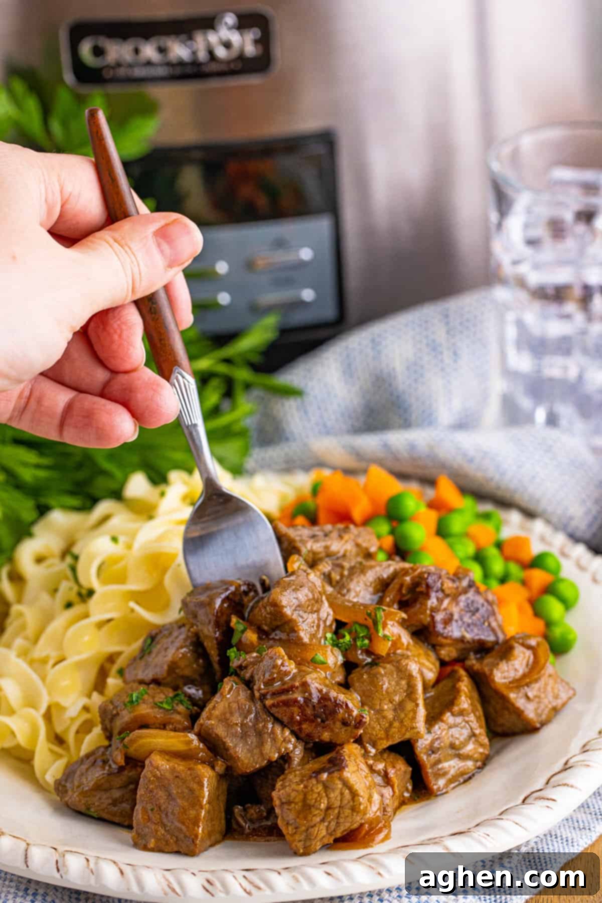 Hand with fork reaching in to take a crockpot steak bite off of plate.