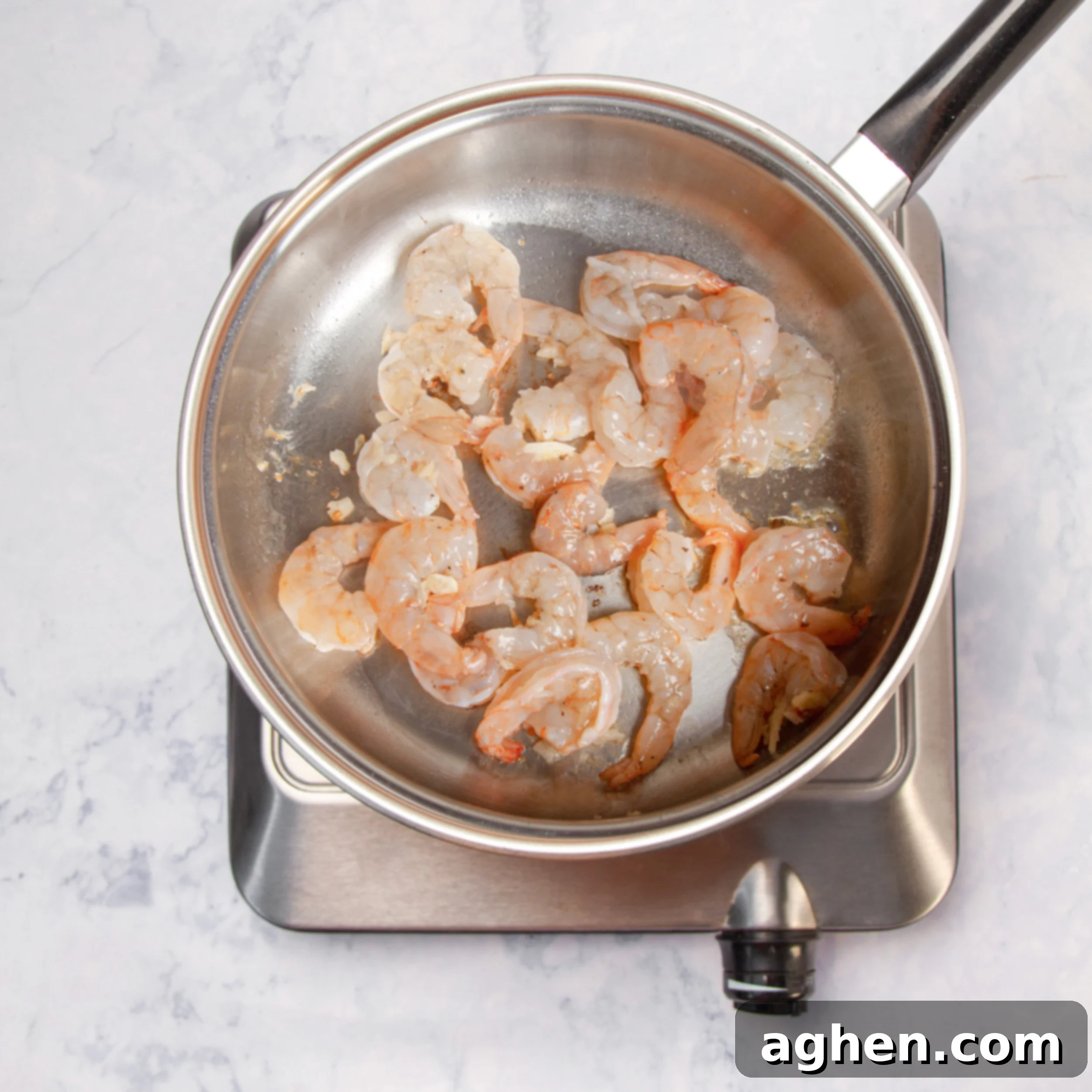 Cooking the shrimp in a skillet, ready to be added to the salad.