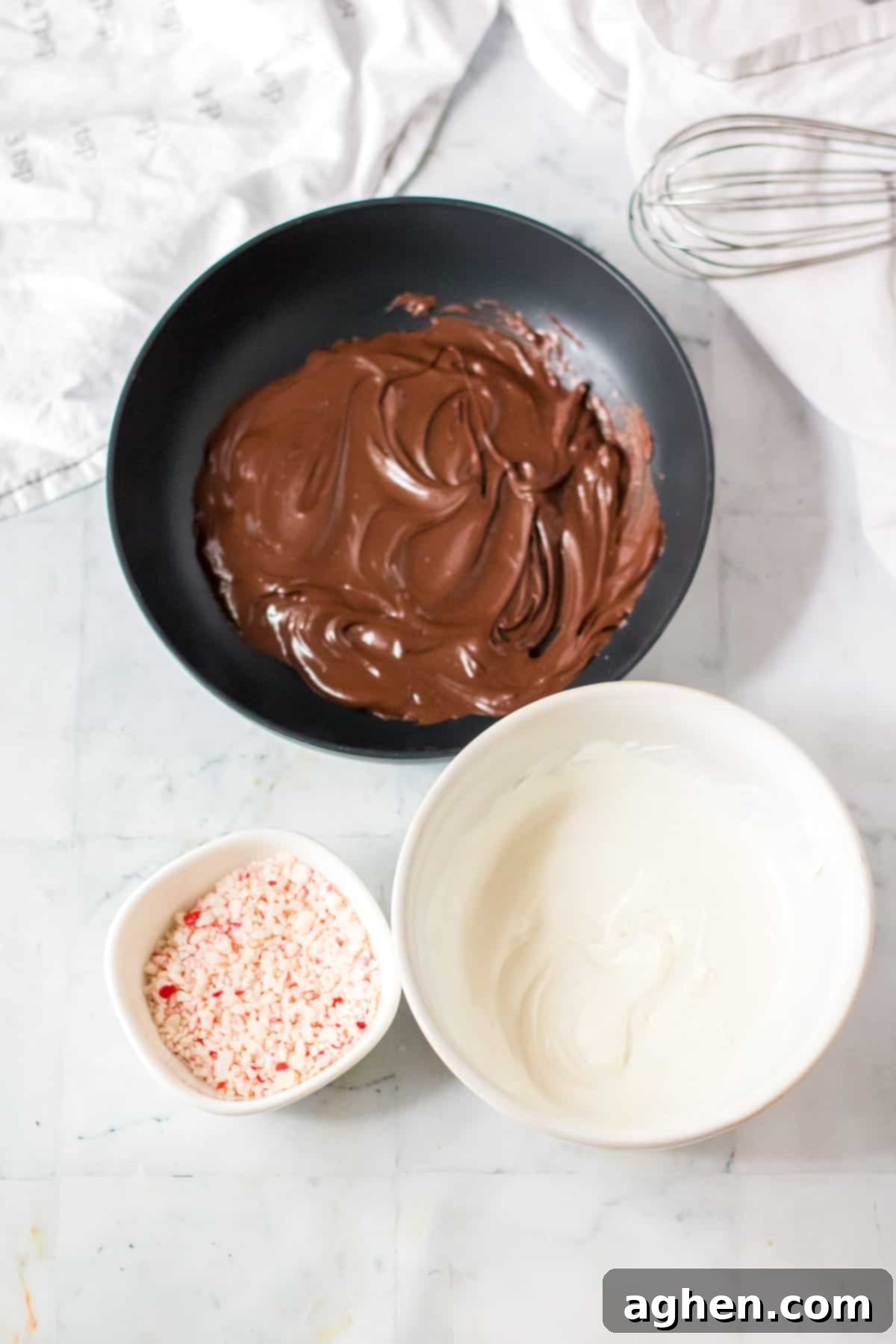 Separate bowls containing melted semi-sweet chocolate, melted white chocolate, and a pile of crushed peppermint candies, ready for making peppermint bark.